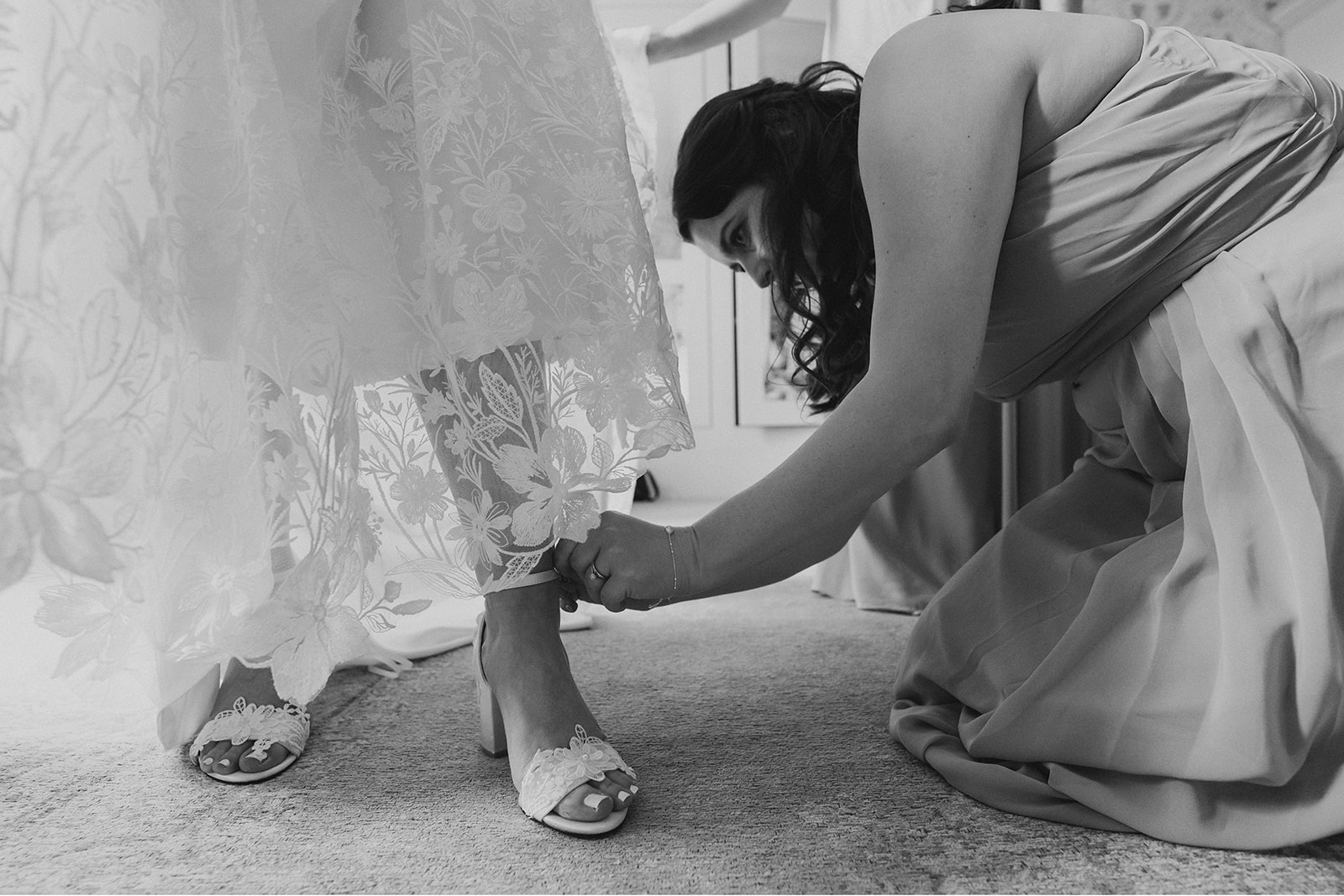 Hodsock Priory Wedding Photography - a bridesmaid helping with the wedding shoes