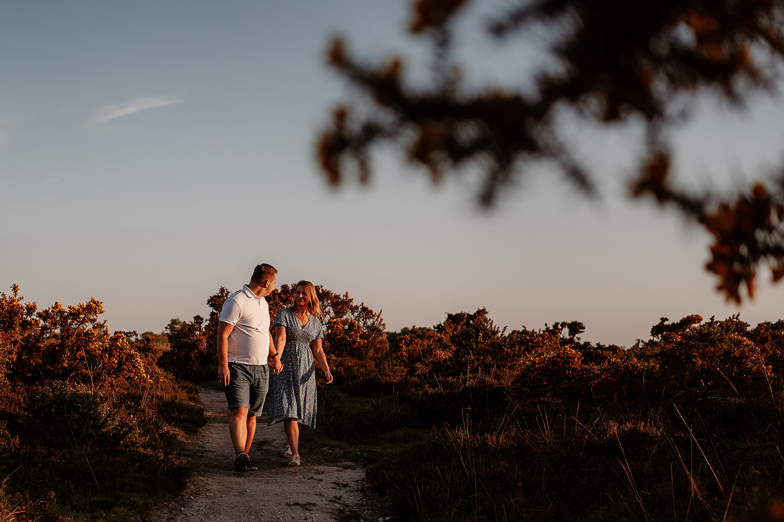 A newly engaged couple walks hand in hand in the New Forest. 