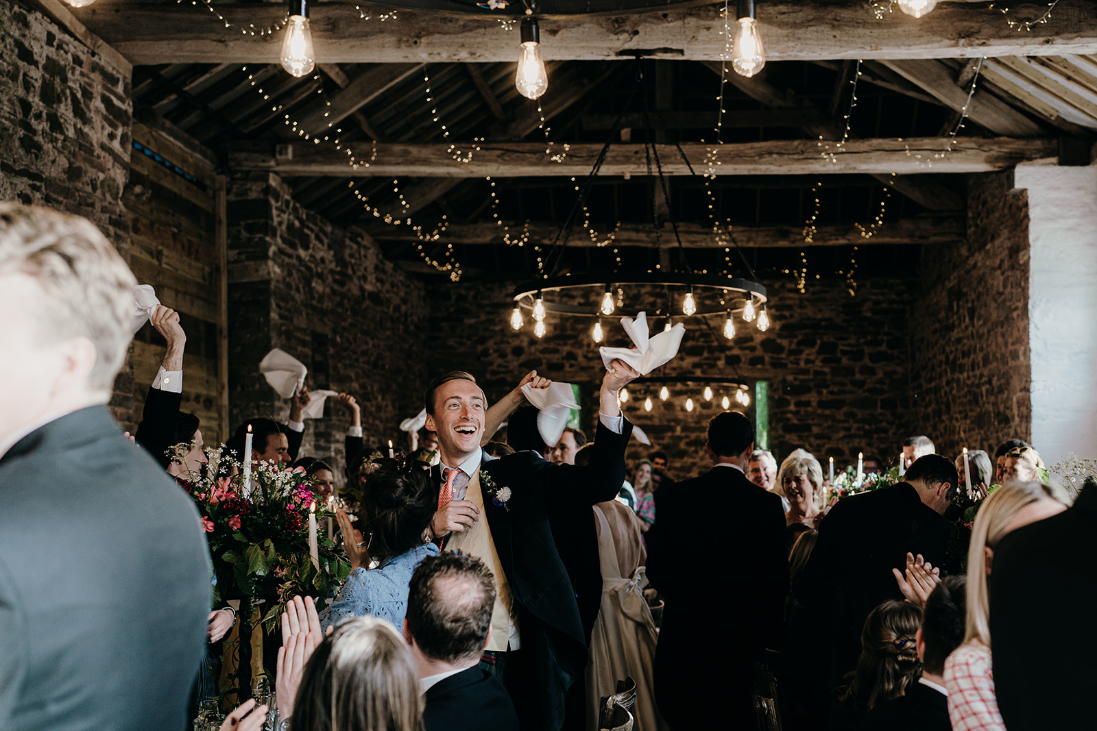 Guests cheering and welcoming in the bride and groom with napkins circling above their heads.