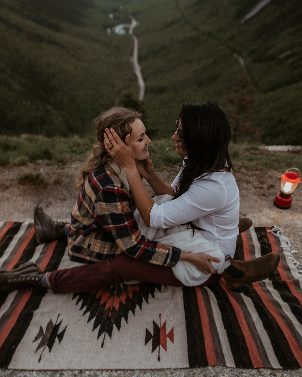 Couple sits together on blanket overlooking Crawford Notch for their White Mountains Adventure Elopement