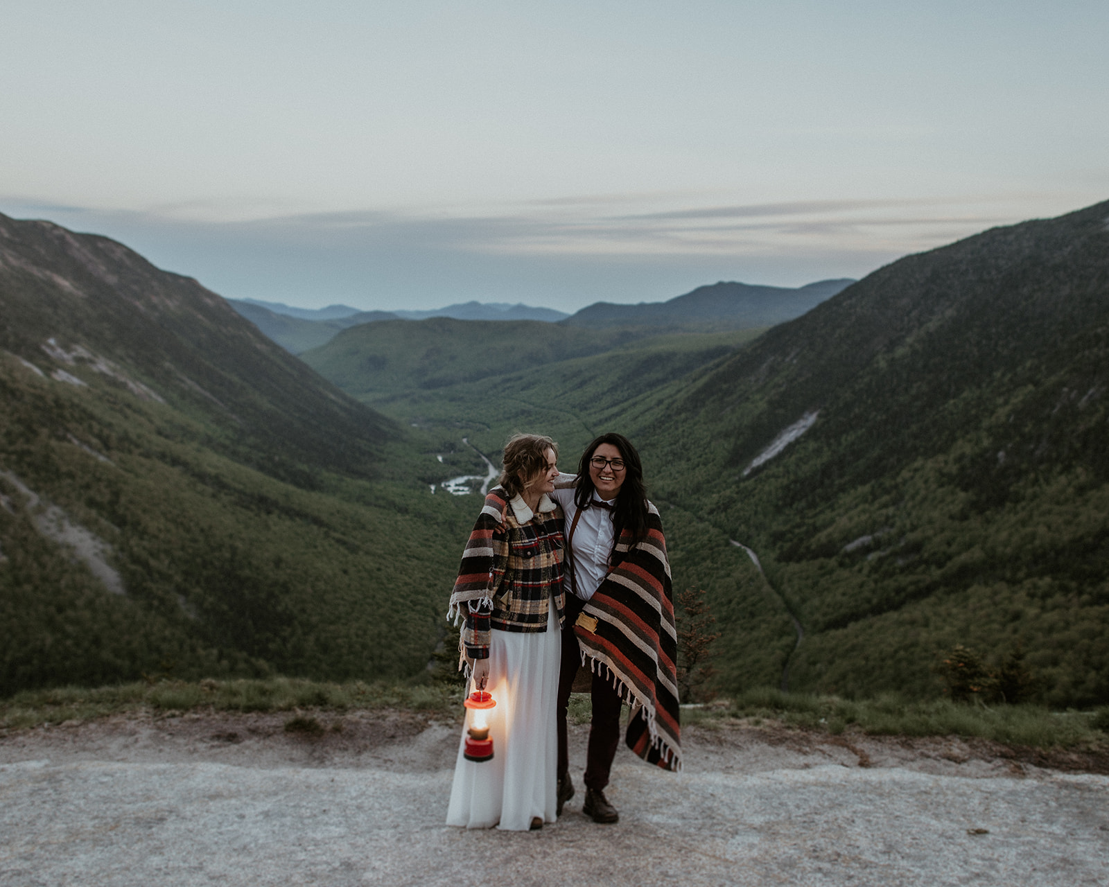 Couple laughs with blanket and lantern during elopement portraits