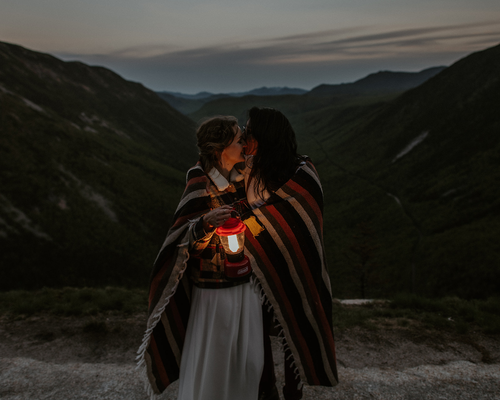 Couple under blanket kisses with lantern