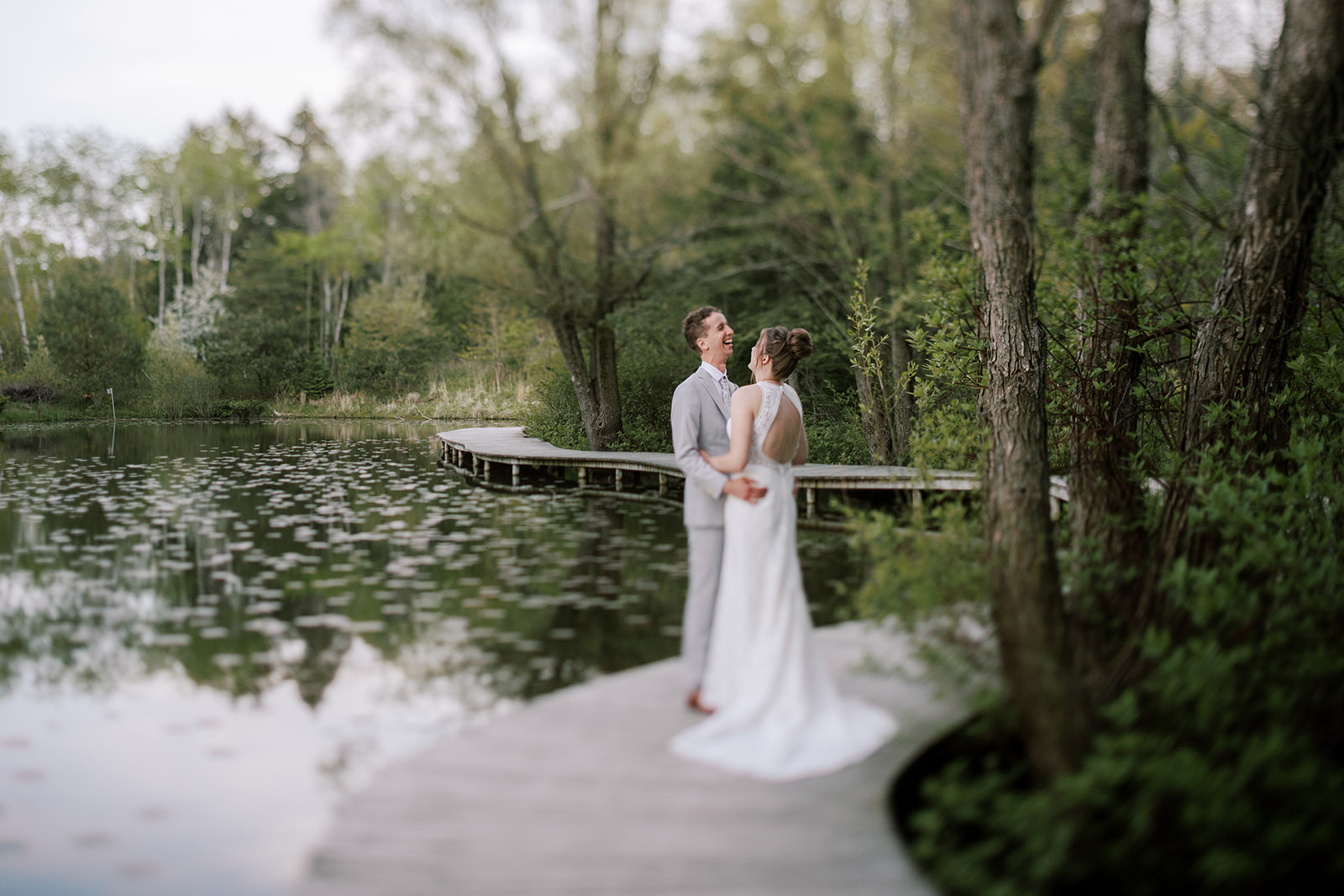bride and groom hold each other and laugh on their wedding day at schlitz audubon nature center in milwaukee wisconsin