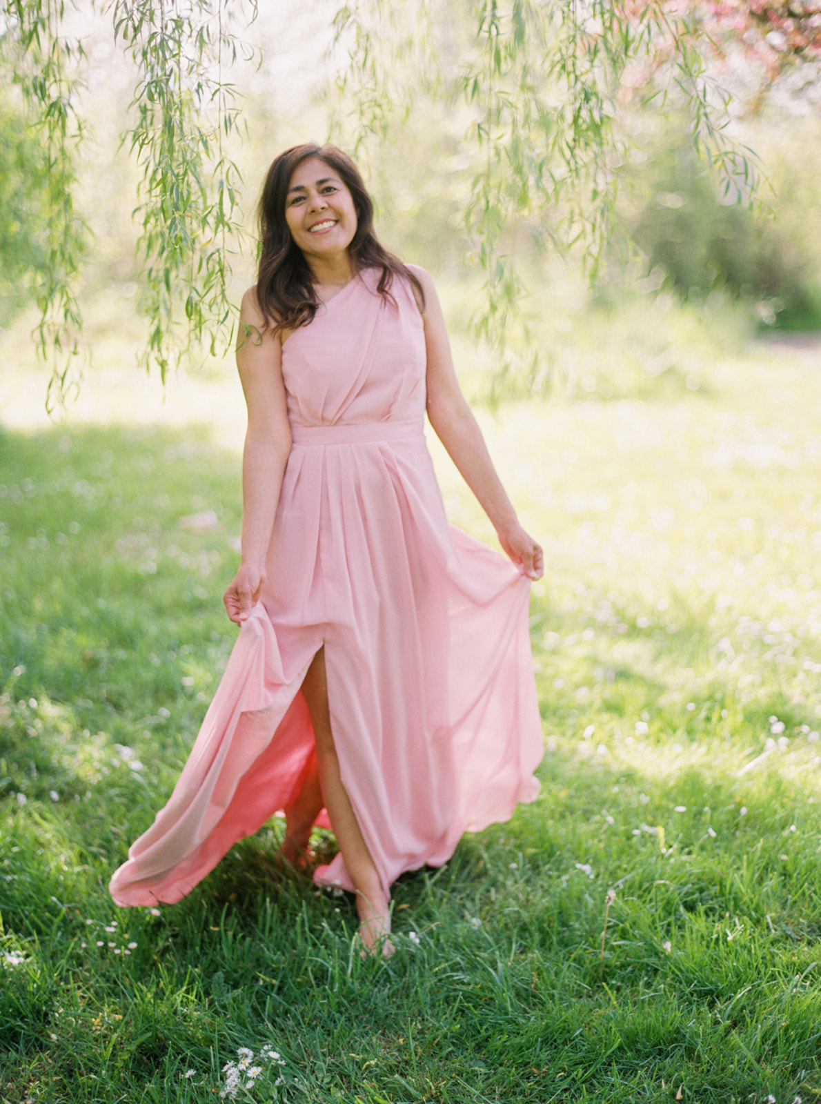 a woman in a pink dress walks through a grassy meadow