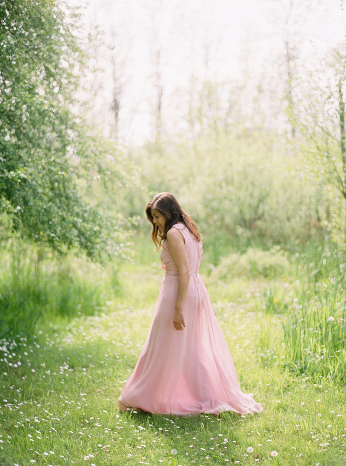 a woman in a pink dress walks by a willow tree