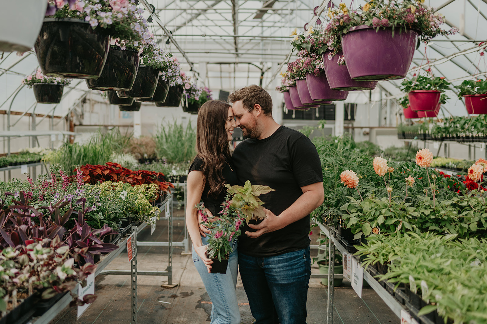A couple shops at a greenhouse together at their engagement session.