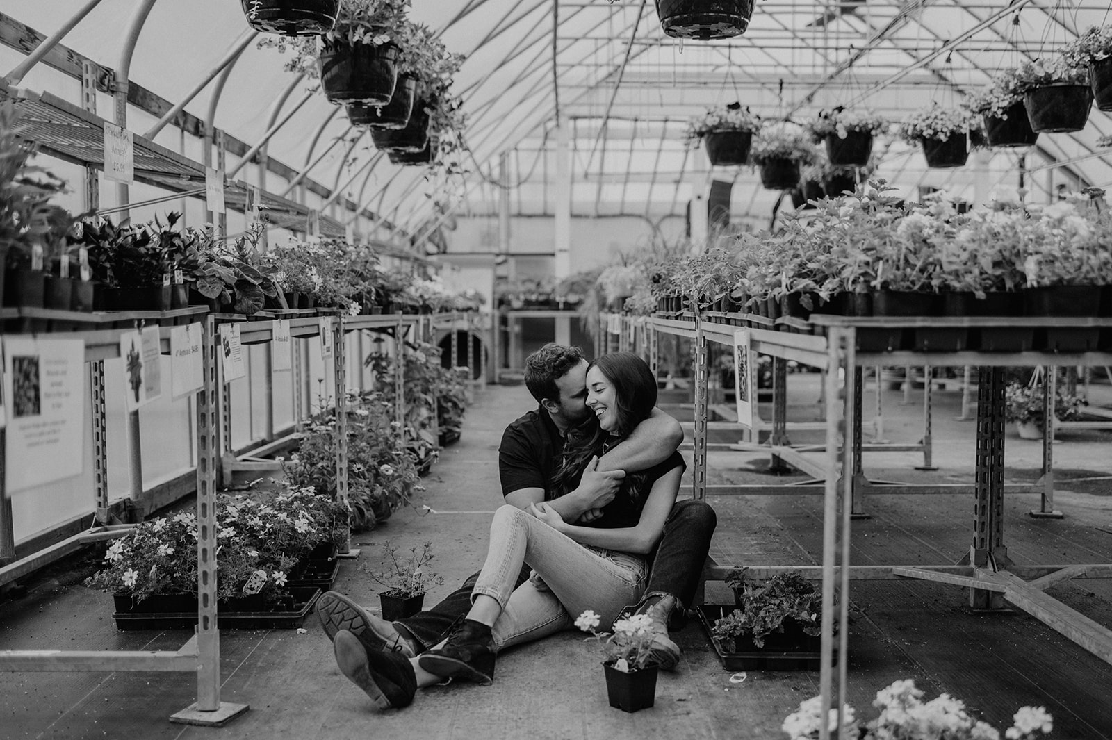 A couple embraces during their greenhouse engagement session.
