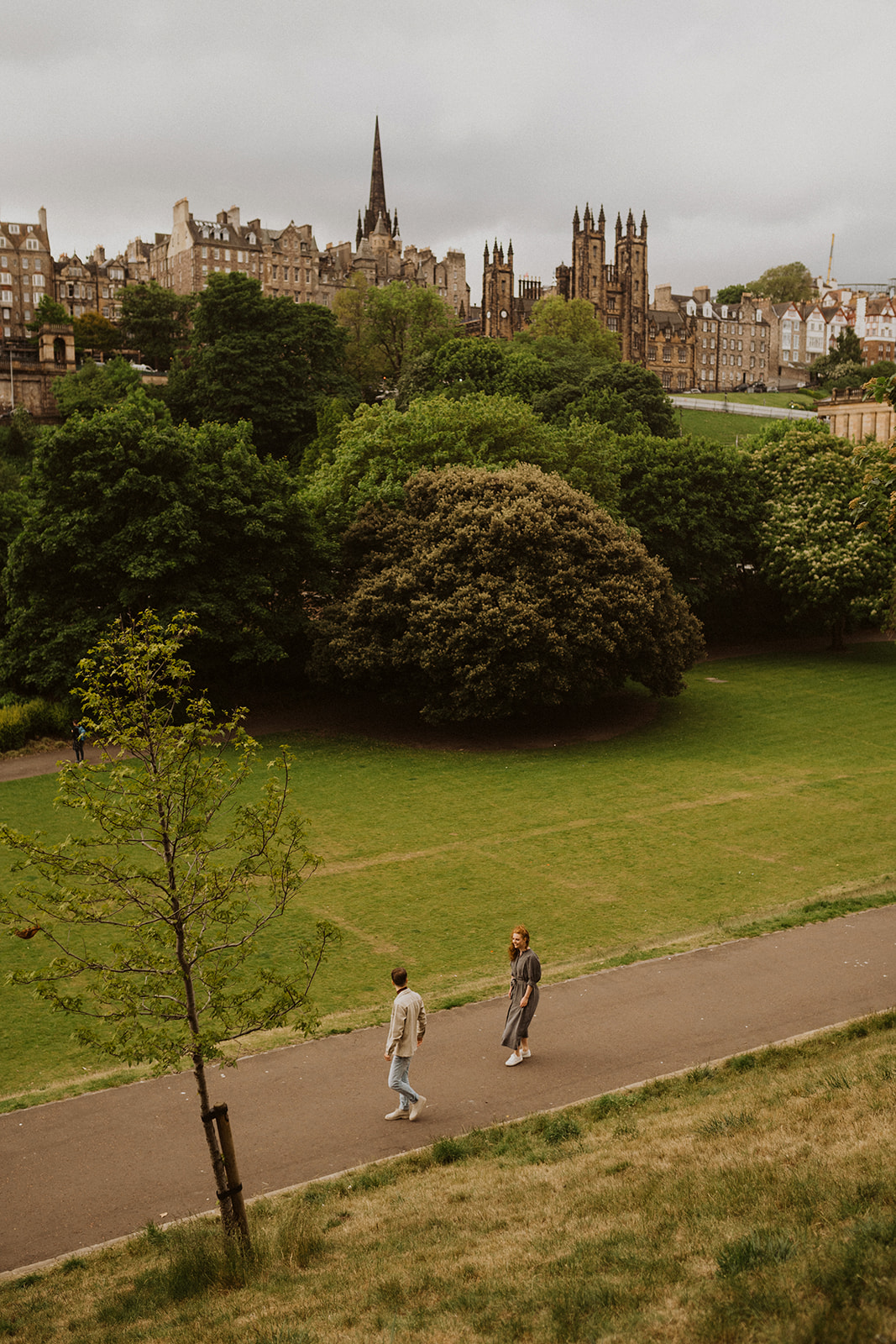 Couple in Princes Street Gardens by Edinburgh Castle walking during photoshoot 