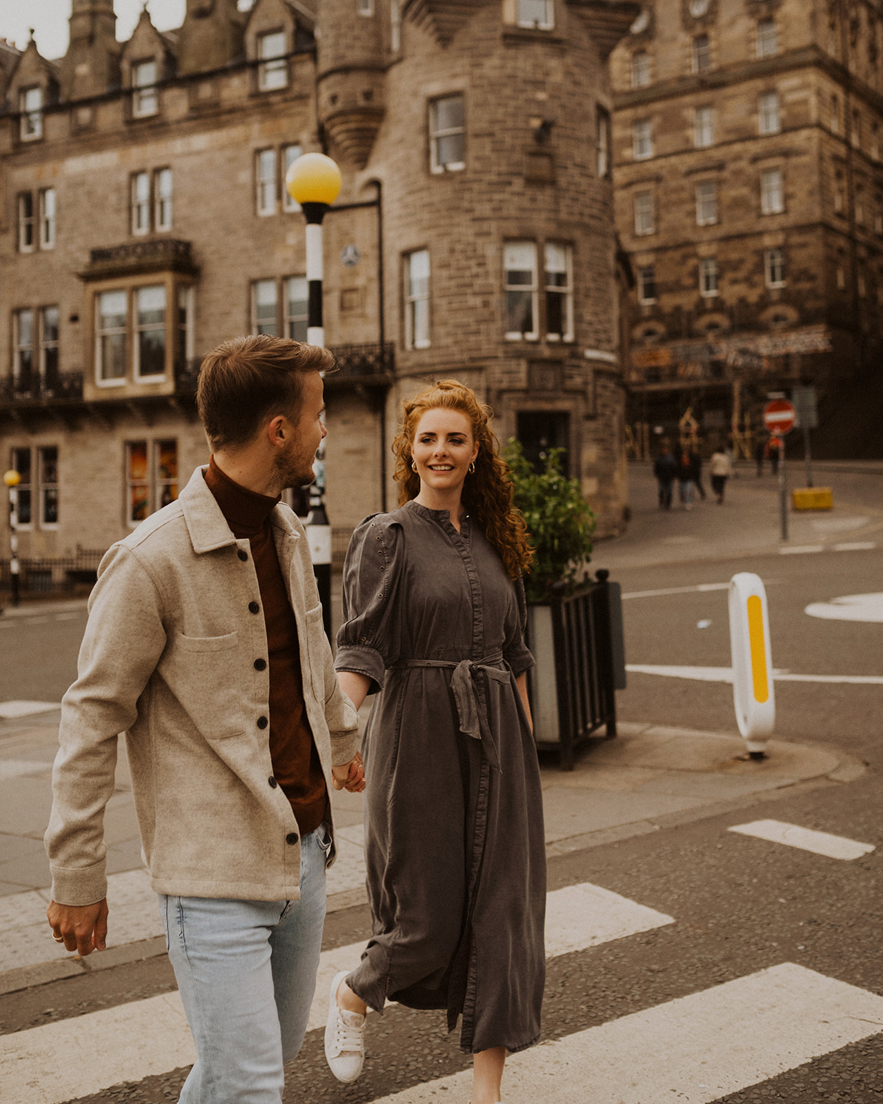 A couple walk holding hands near Edinburgh Royal Mile during photoshoot