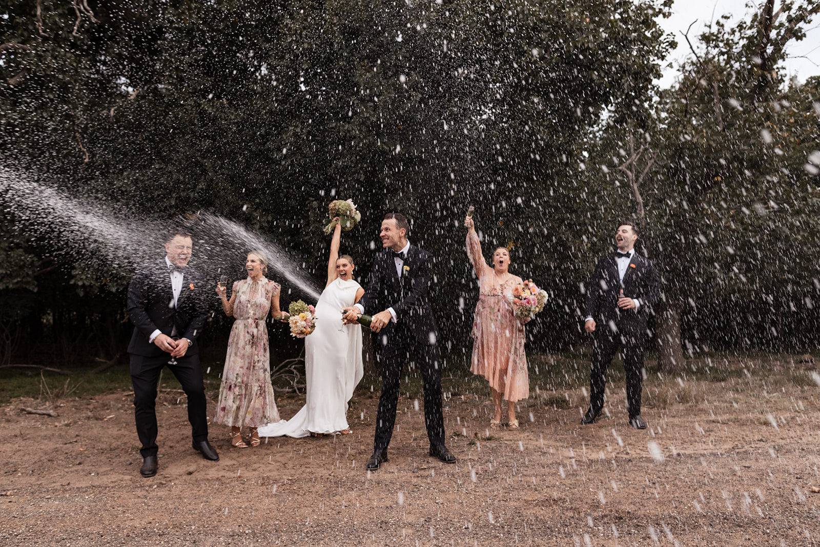 Groom sprays champagne in front of his bridal party