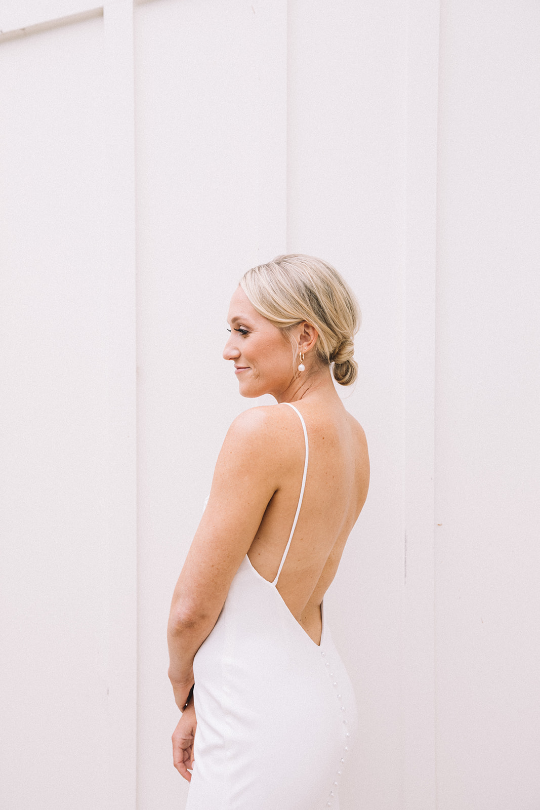 Bride wears a classic wedding dress with a low back and buttons. 