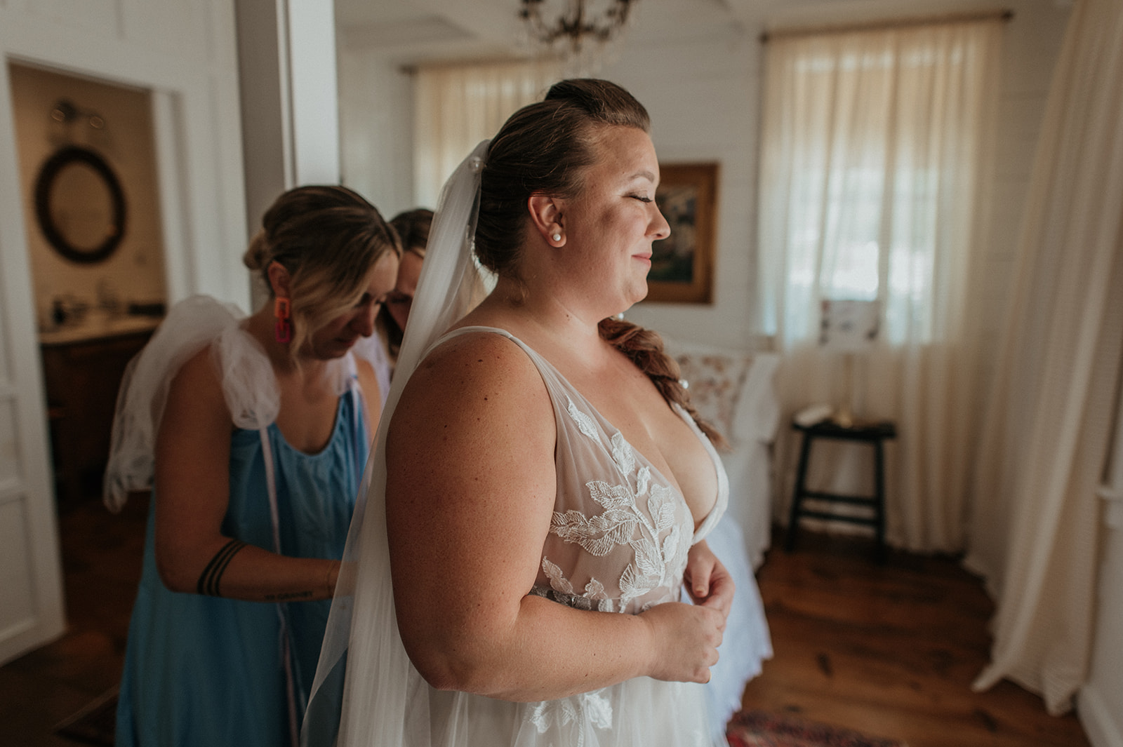Bridesmaids help zip bride into willow by watters wedding gown
