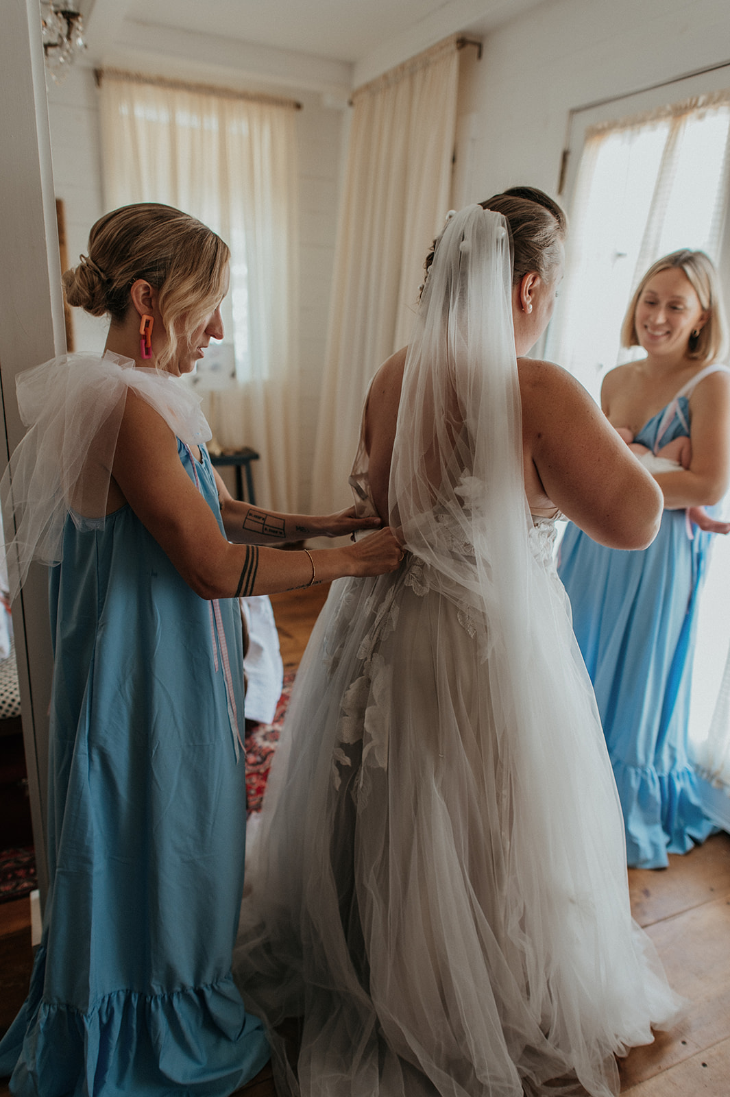 Bridesmaids help zip bride into willow by watters wedding gown