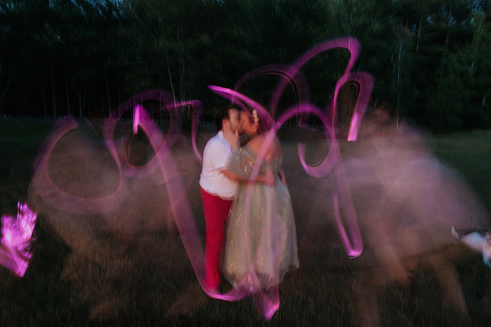 Bride and groom kiss during long exposure photo with glow sticks