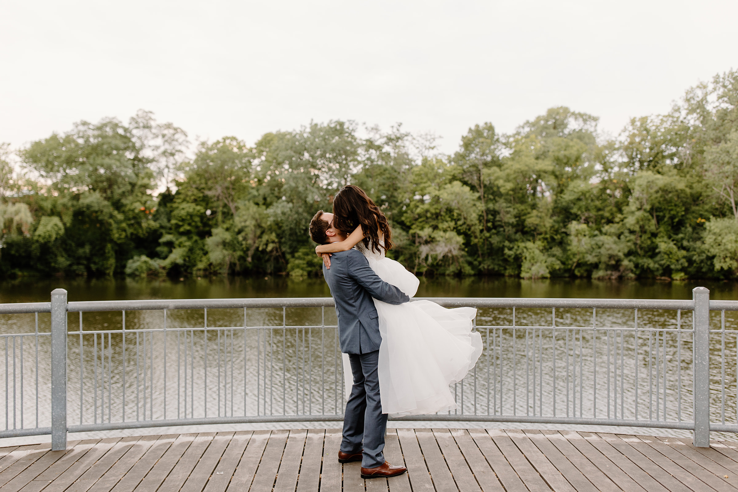 Groom lifting his bride up in front of a river