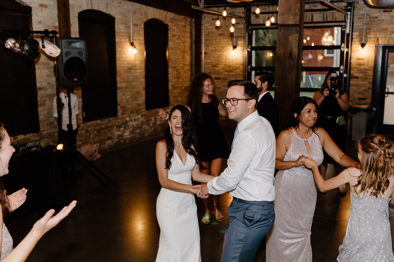 Bride and groom dance with guests on the dance floor