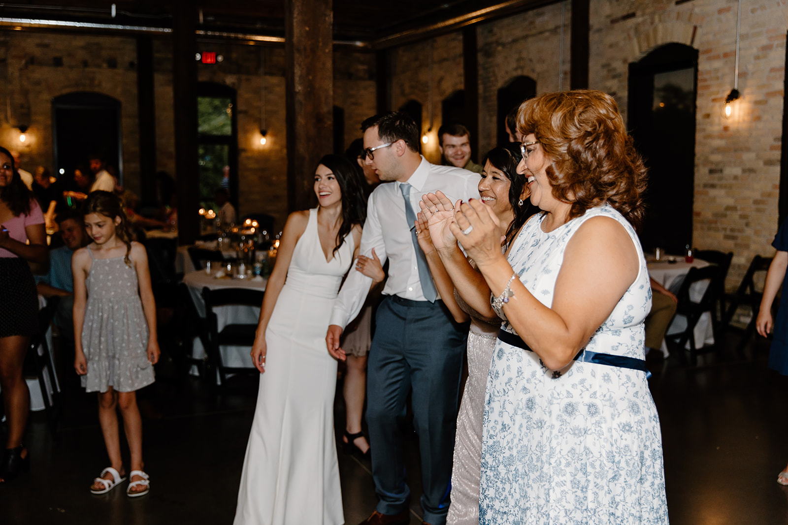 Bride and groom dance with guests on the dance floor
