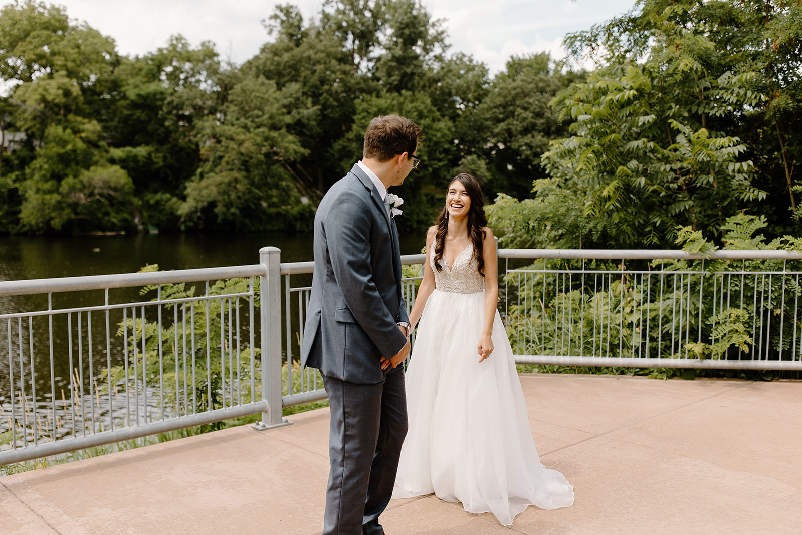 Bride laughs at her groom in front of a river