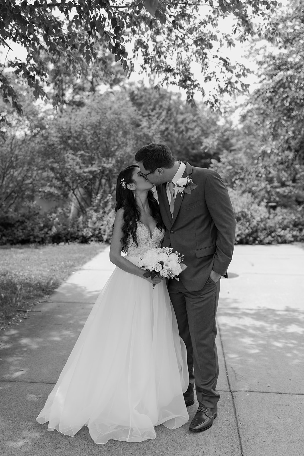 Bride and groom share a kiss in front of some trees