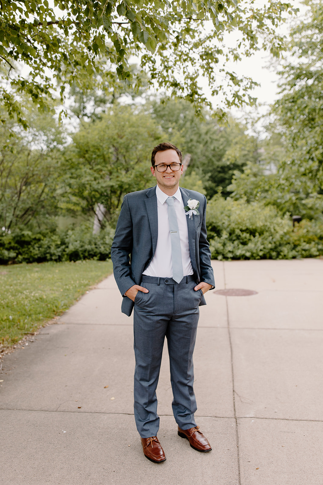 Groom smiles at the camera with his hands in his pockets