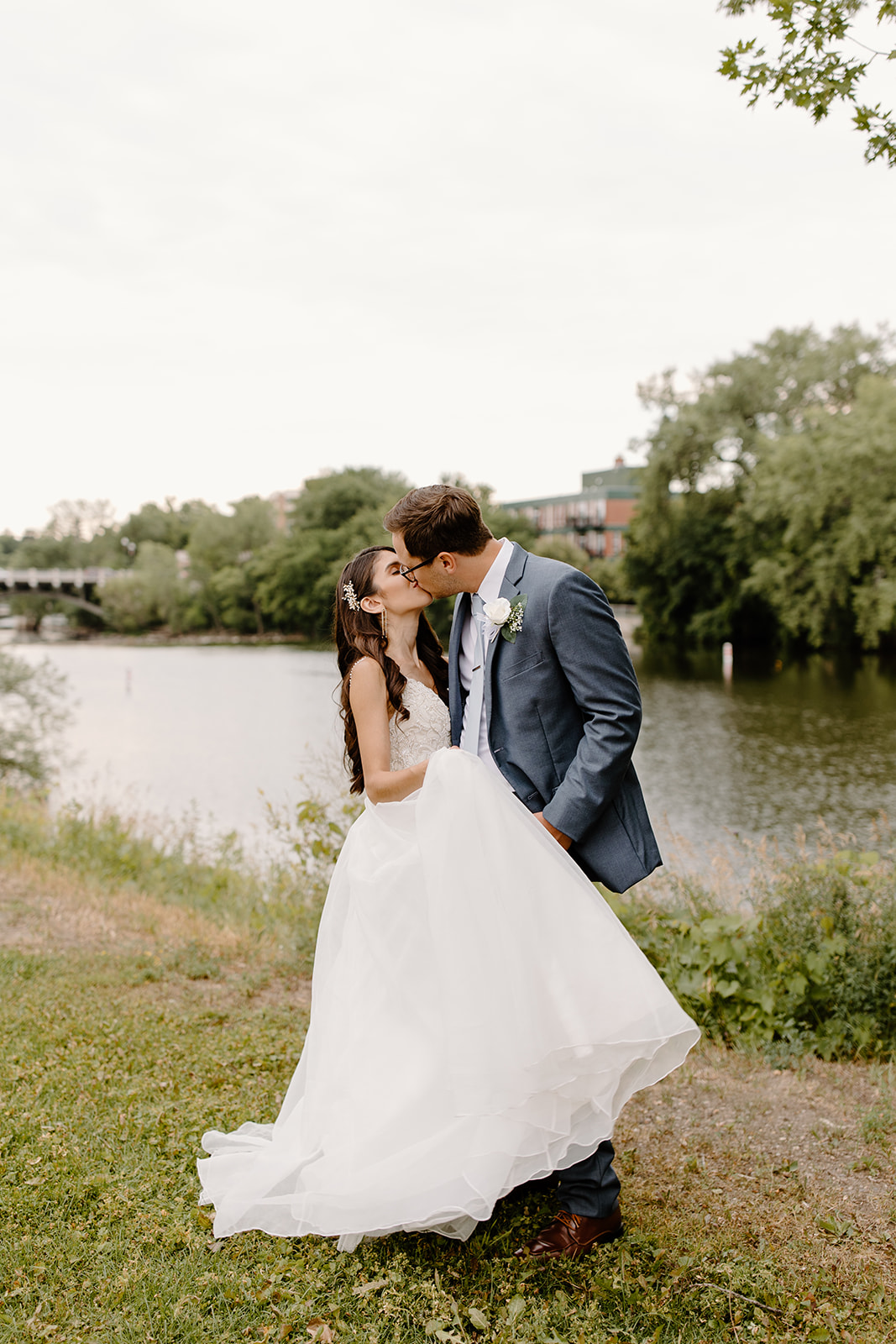 Bride and groom kiss in front of a river