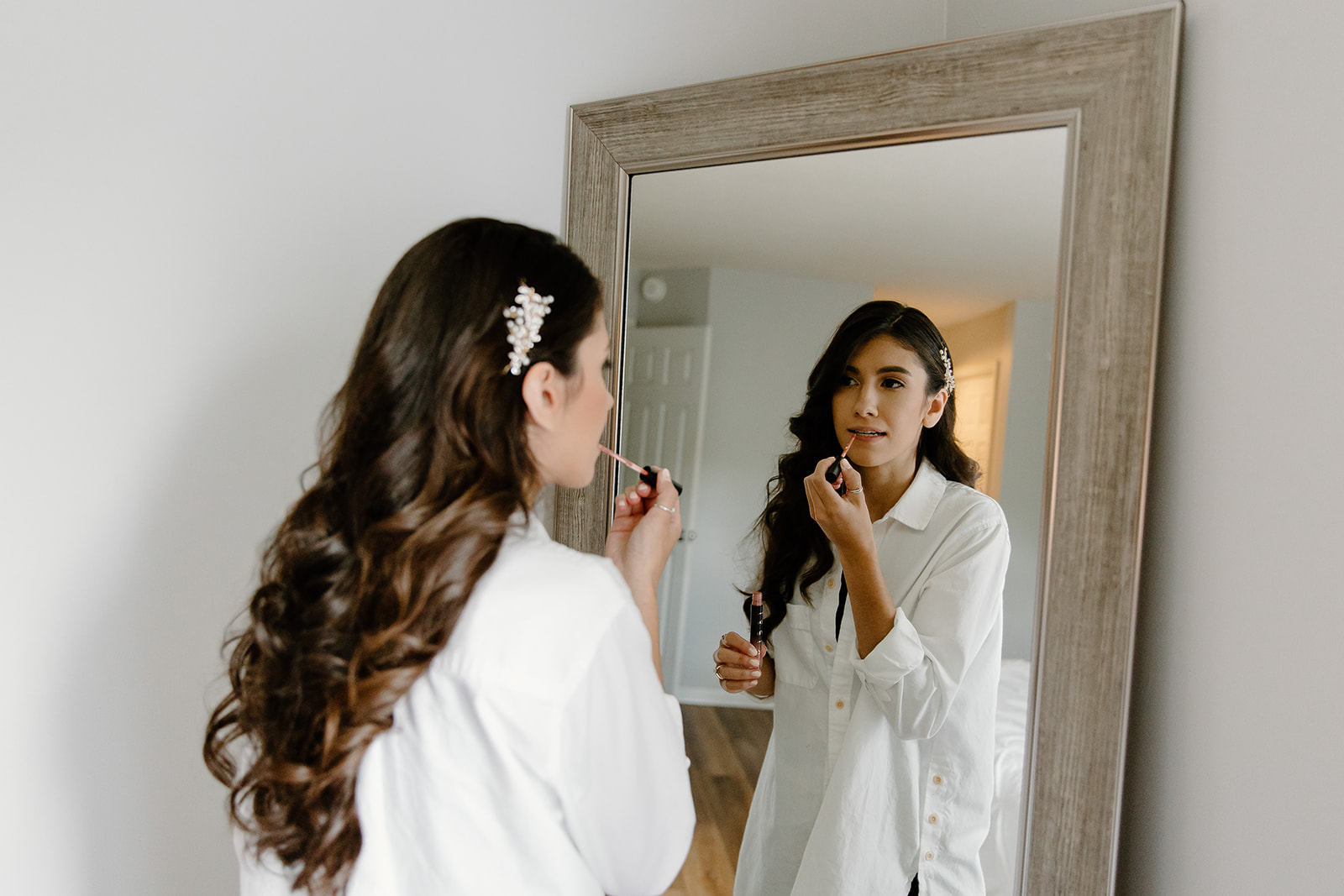 Bride applying lipgloss in front of a mirror