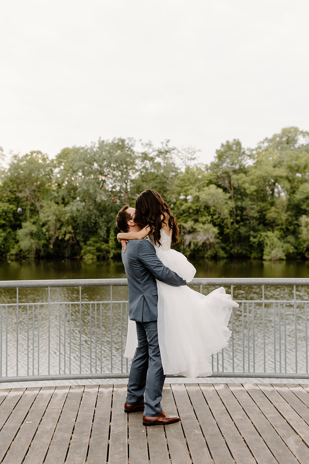Groom lifts his bride in front of a river