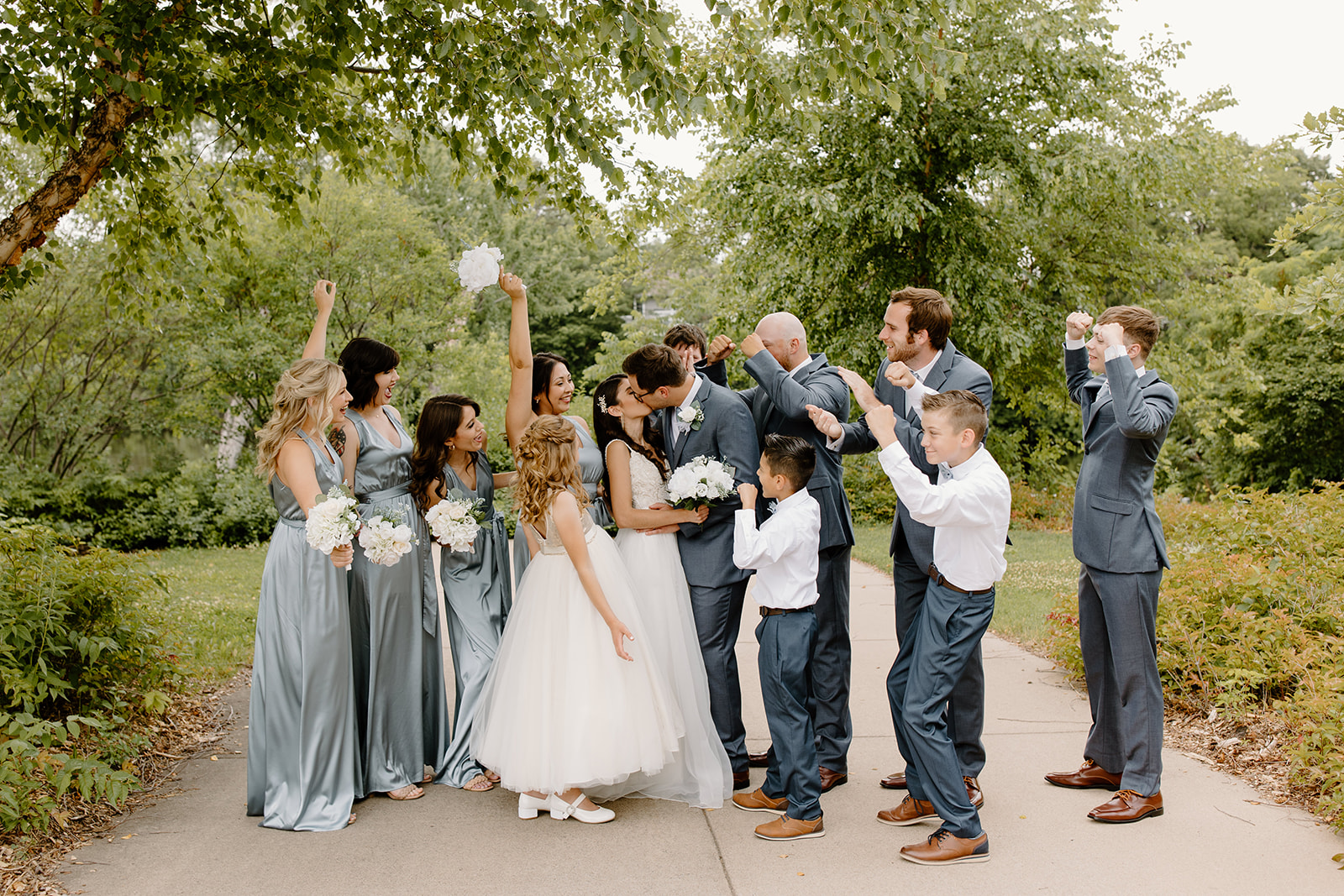 Bride and groom kiss while their wedding party cheers them on