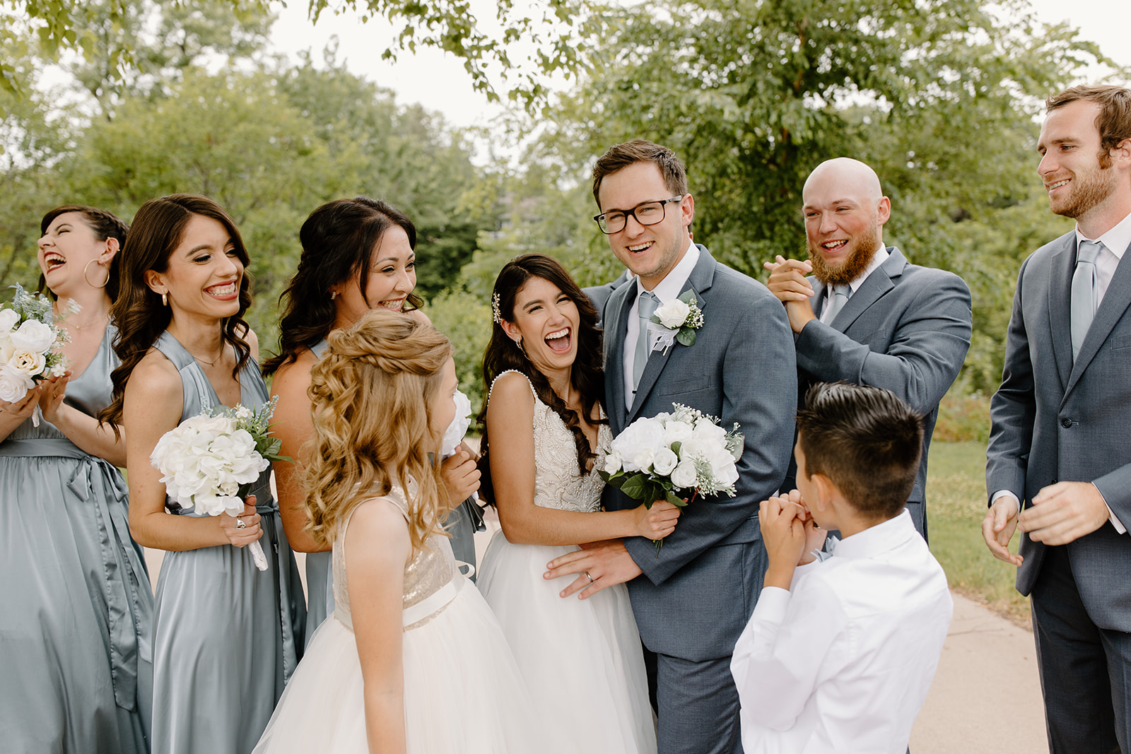 Bride and groom laugh surrounded by their wedding party