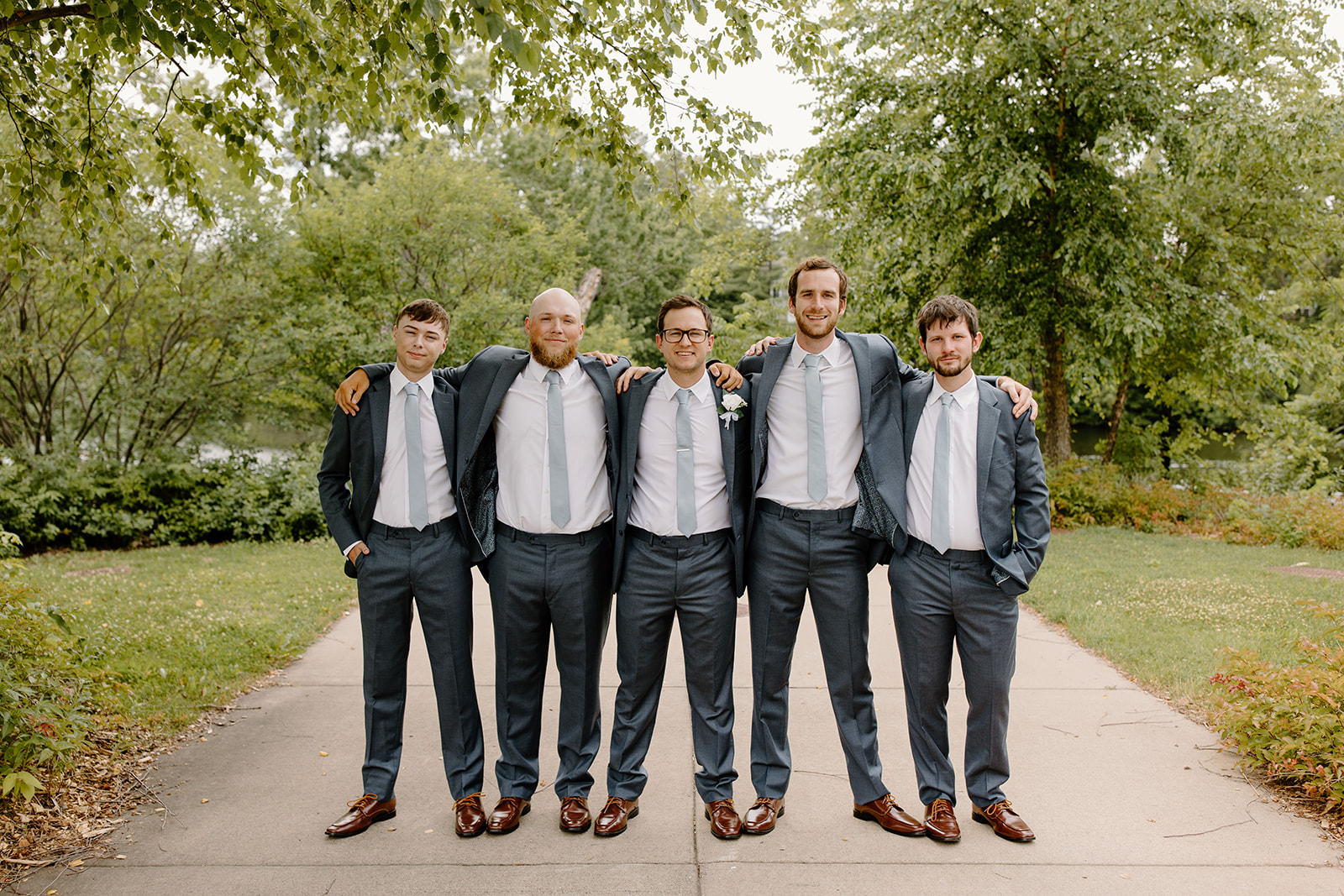Groom and his groomsmen smile with their arms around each other