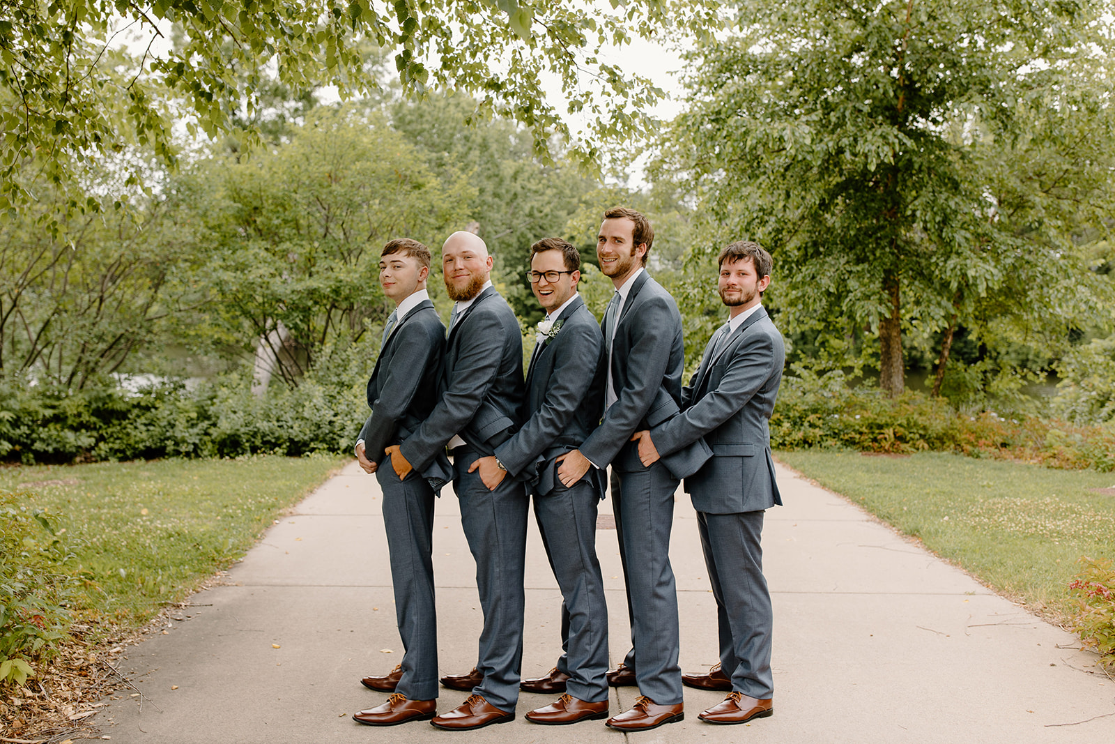 Groom and his groomsmen hold each other in a prom pose