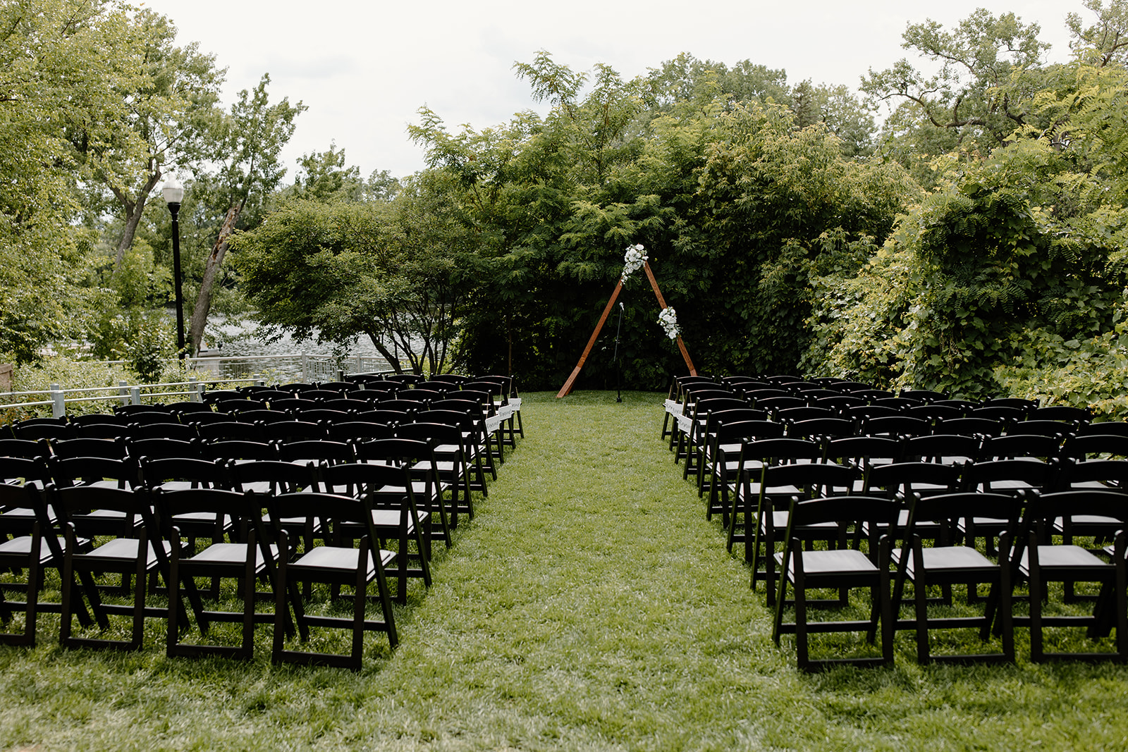 Chairs and an arch set up for a wedding ceremony in front of trees