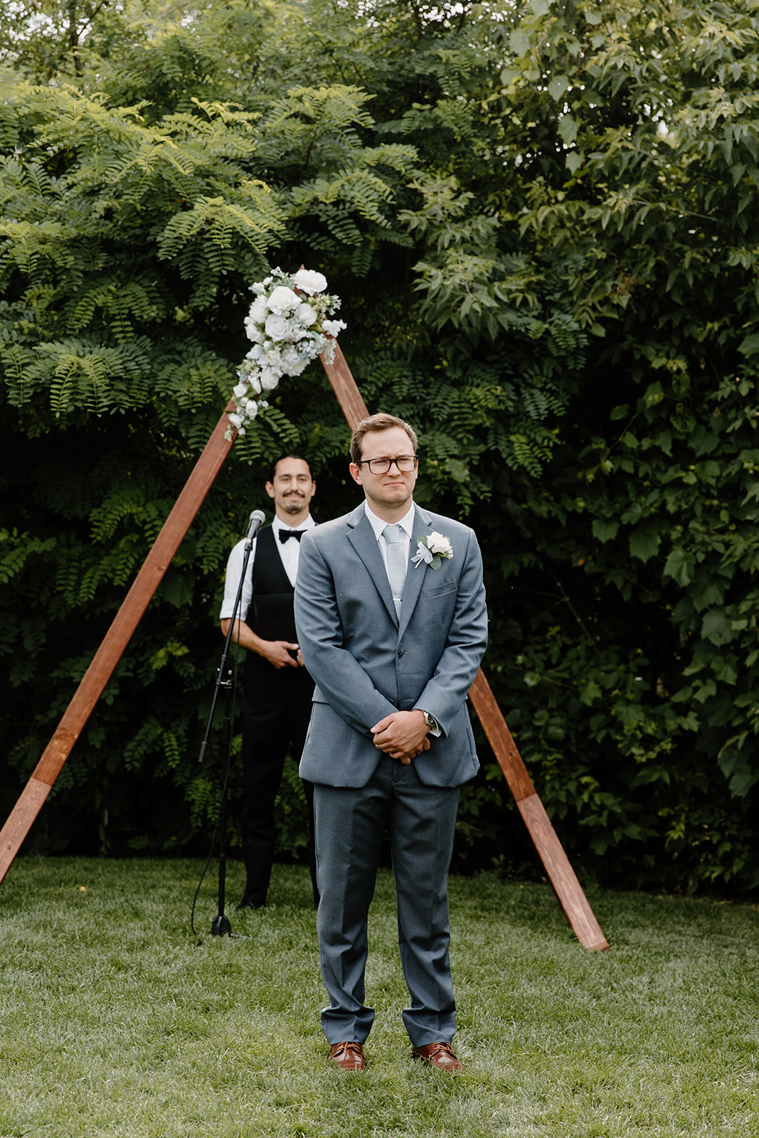 Groom smiles in front of an arch