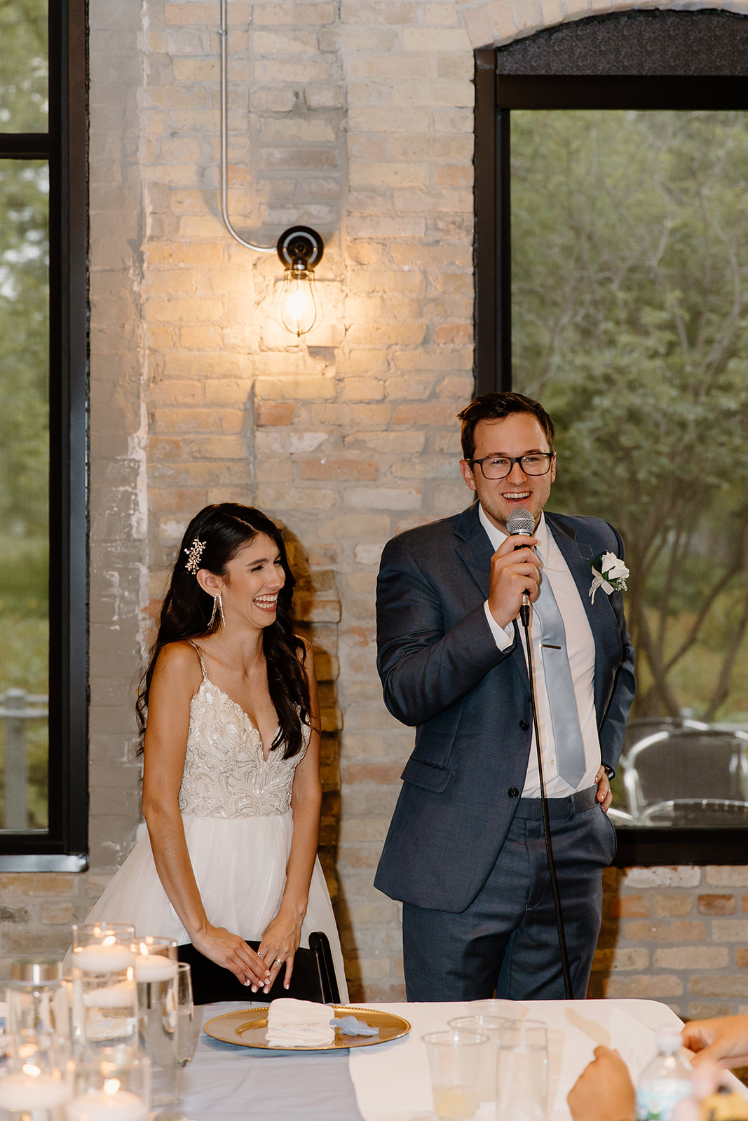 Groom and bride stand up next to their dinner table and give a speech