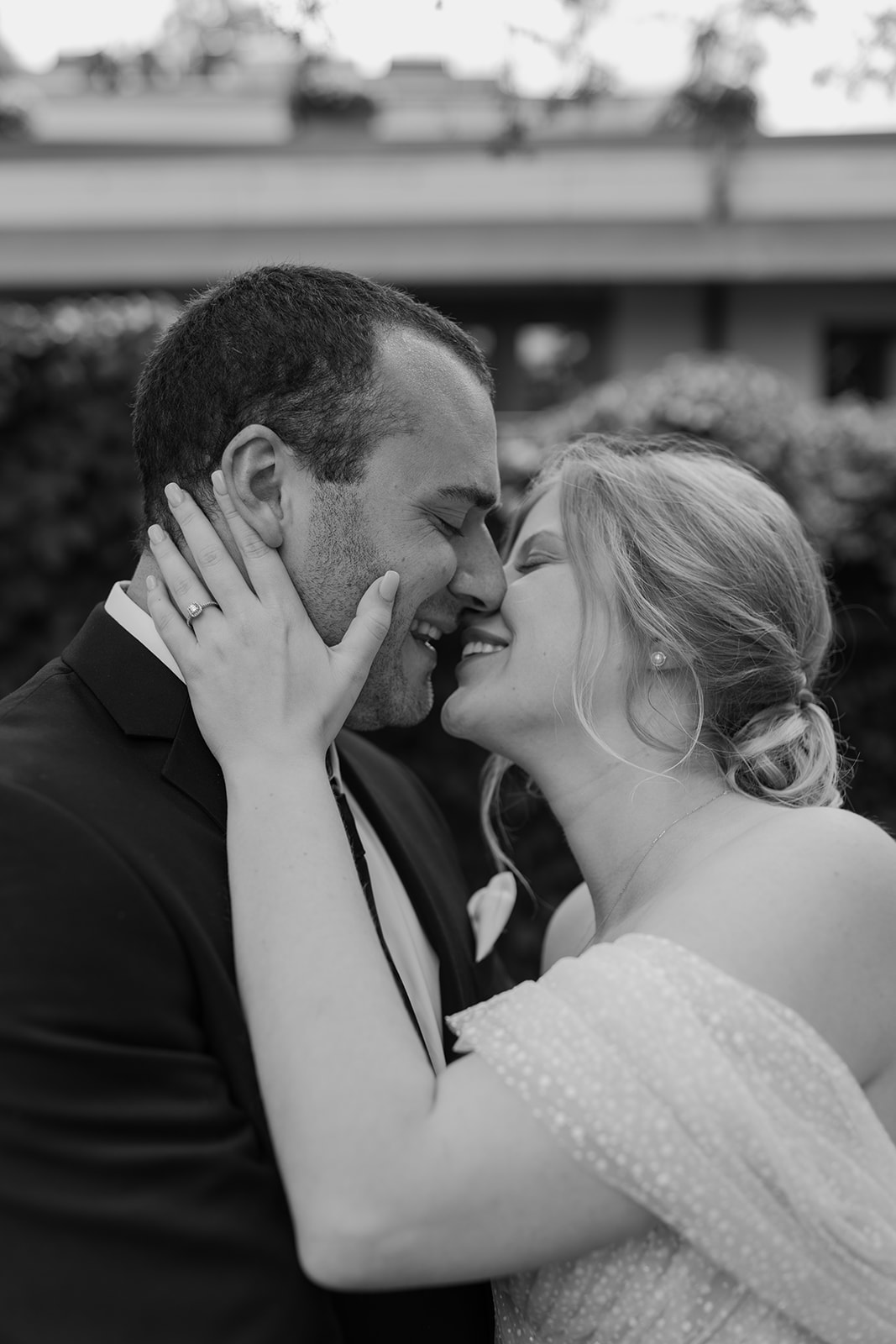 Bride holds her groom's face as she kisses him