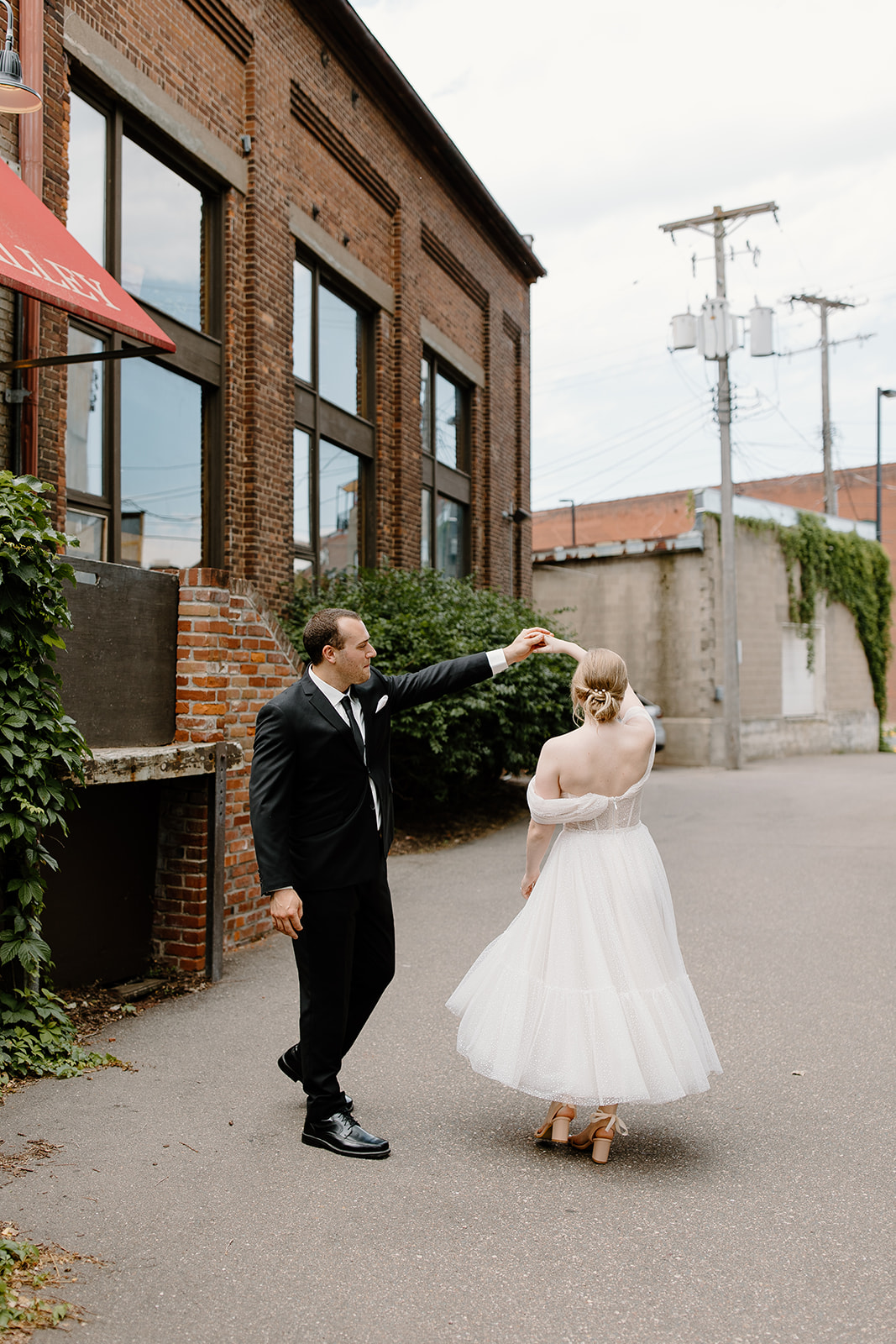Groom twirls his bride in an alley