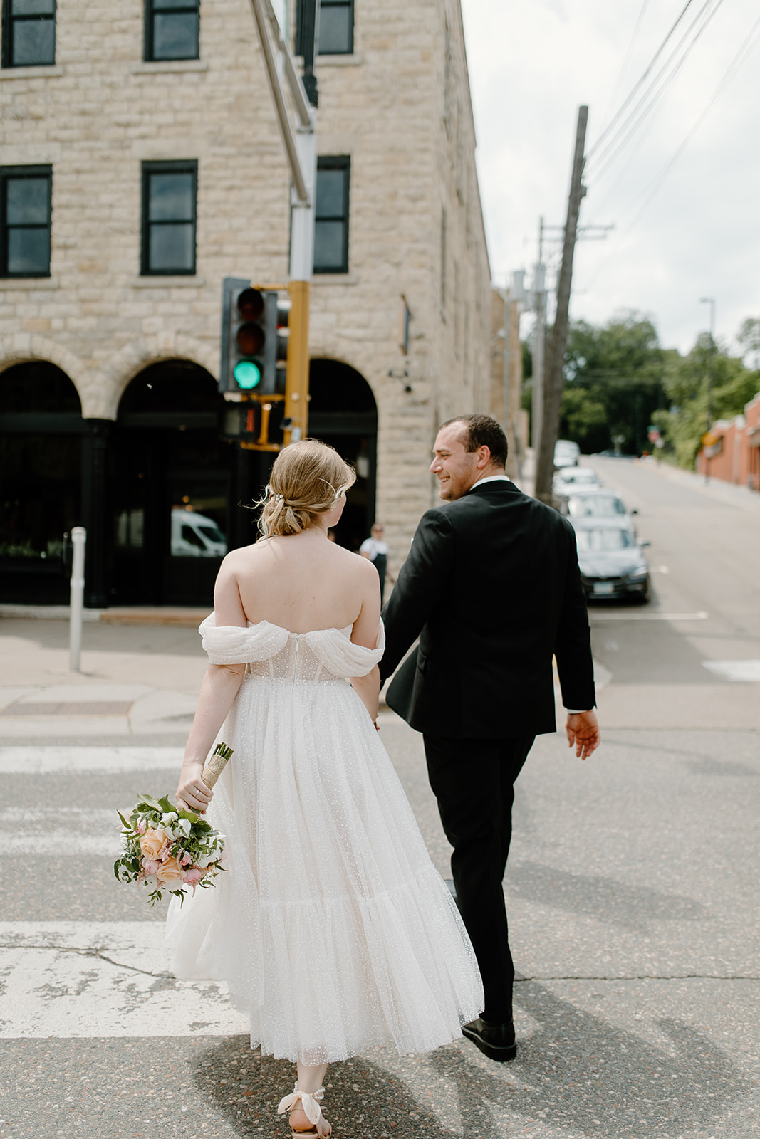 Bride and groom hold hands and walk across the street