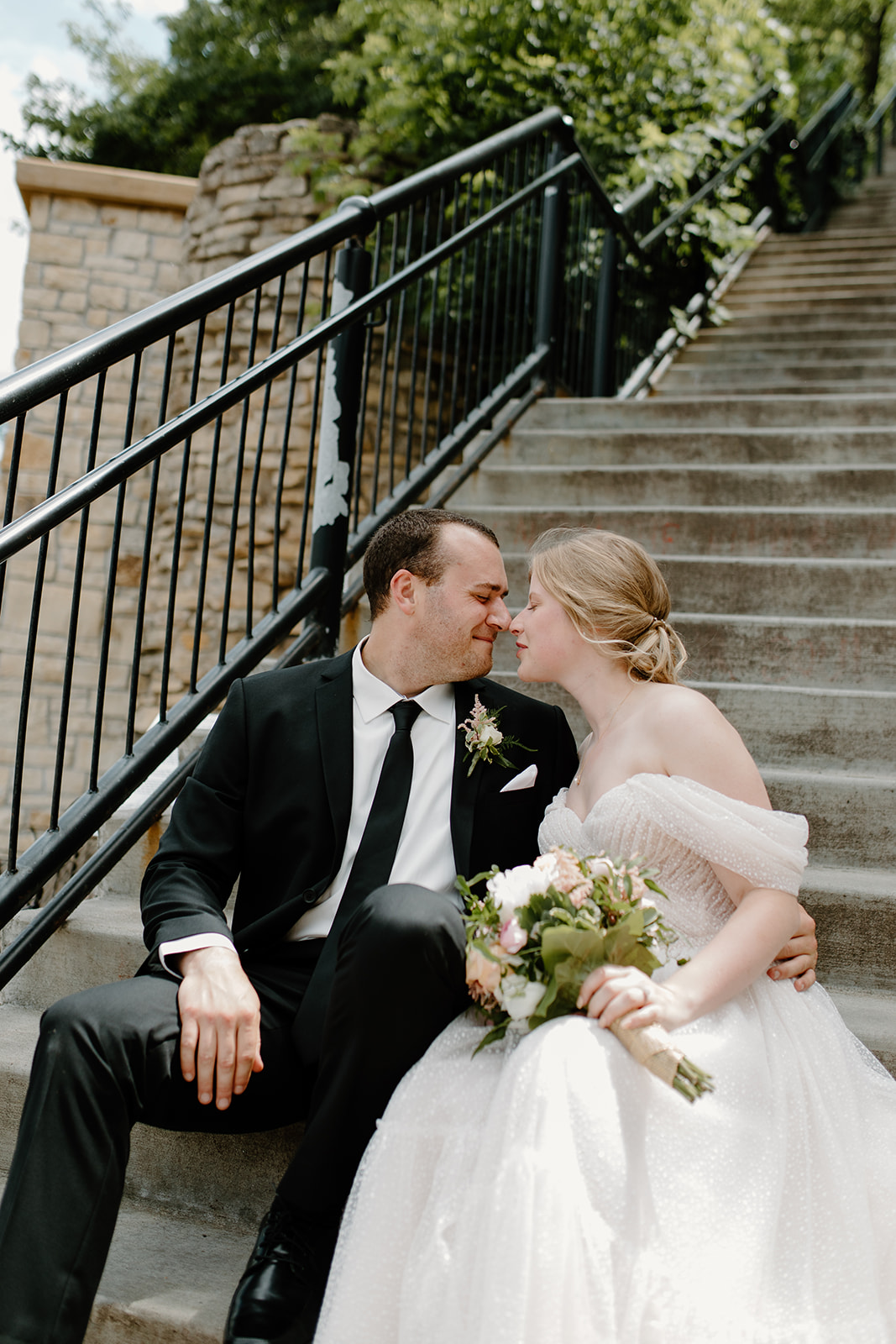 Bride and groom sitting on a staircase smiling at each other
