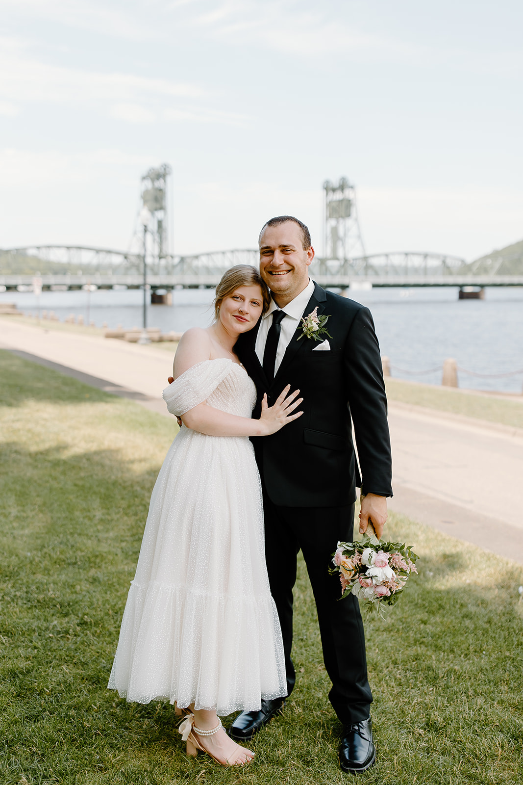 Bride and groom smiling in front of a lift bridge on the St. Croix river