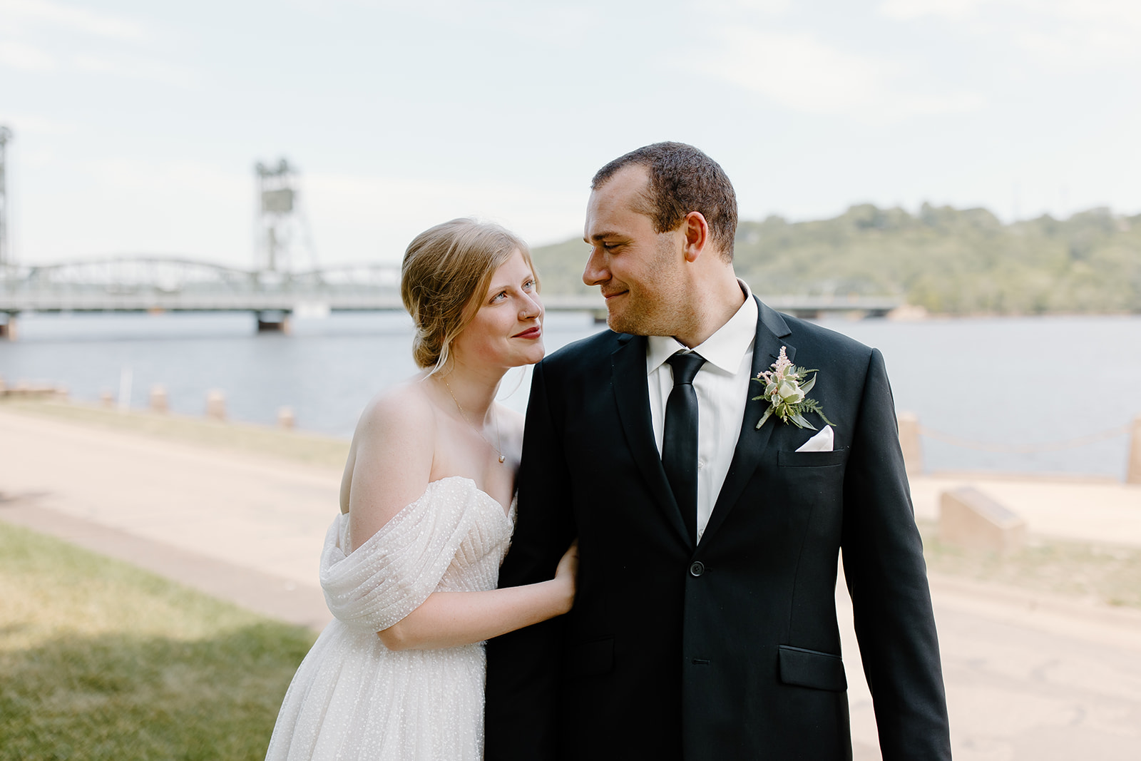 Bride and groom smiling in front of a lift bridge on the St. Croix river