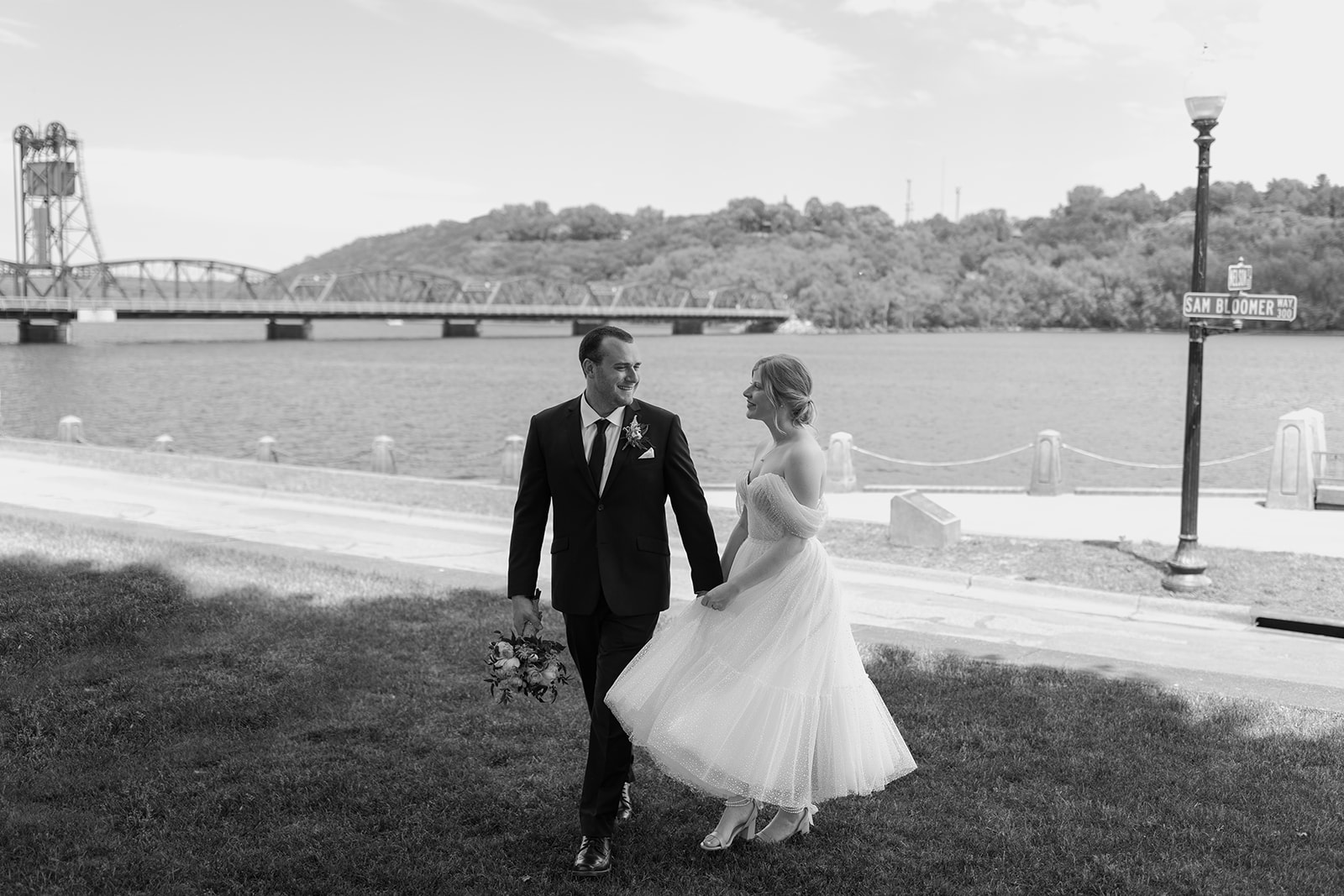 Bride and groom walking in front of a lift bridge on the St. Croix river