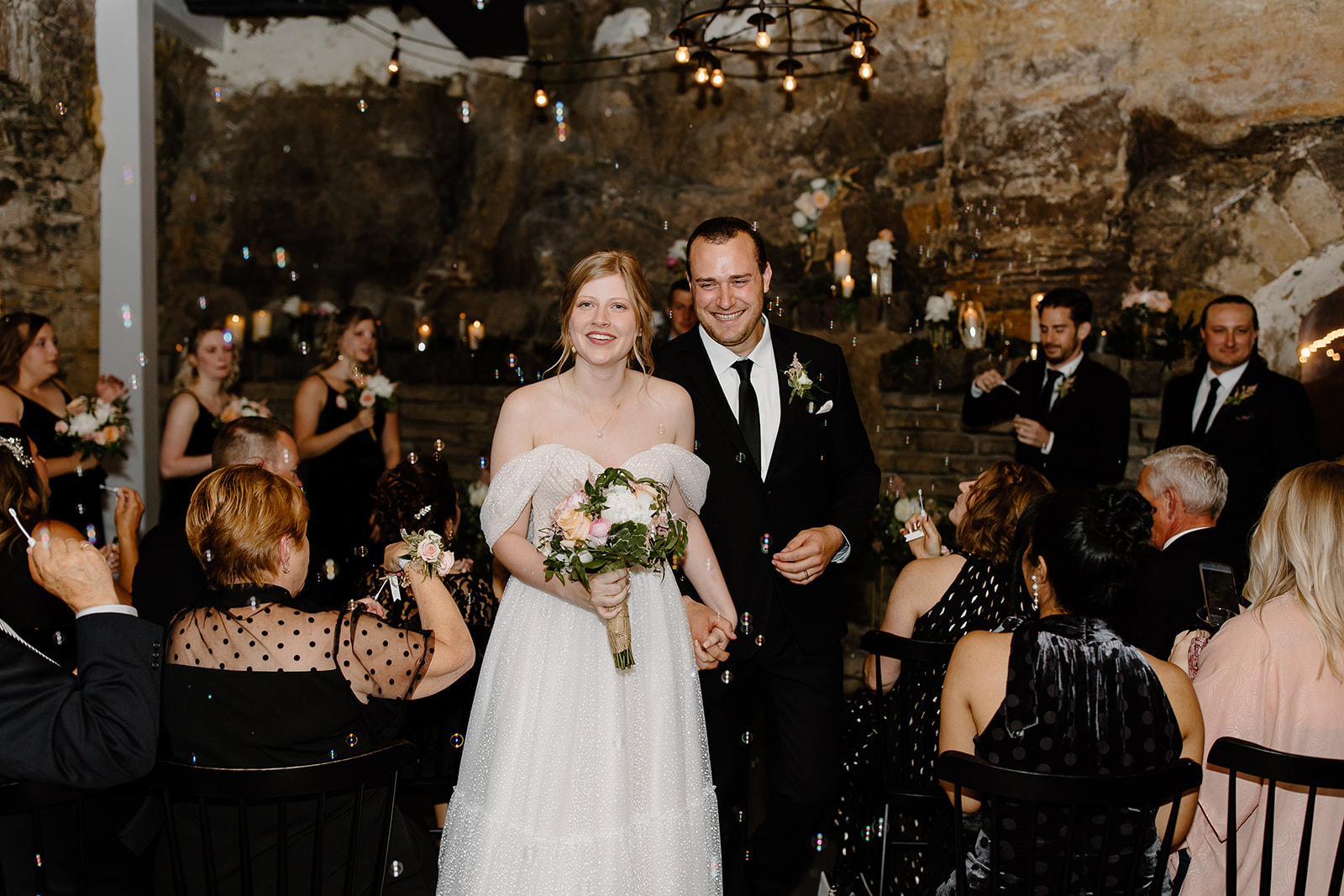 Bride and groom walking out of their ceremony in a cave