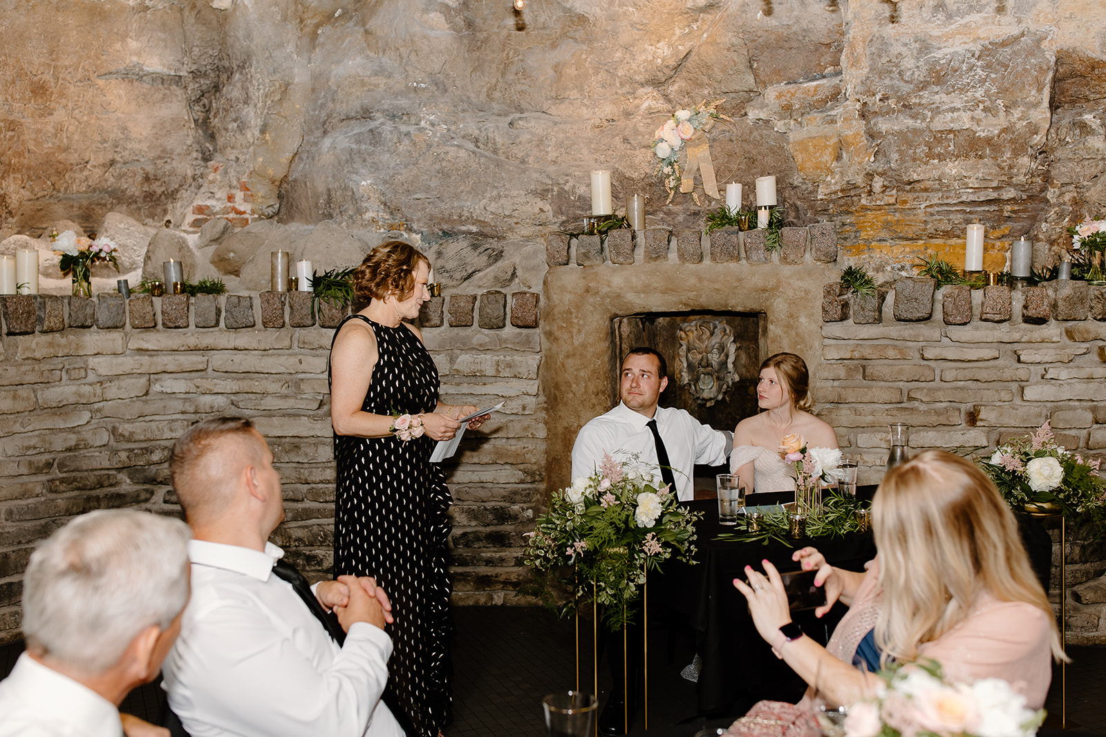 Bride and groom listen to speeches given at their wedding reception in a cave 