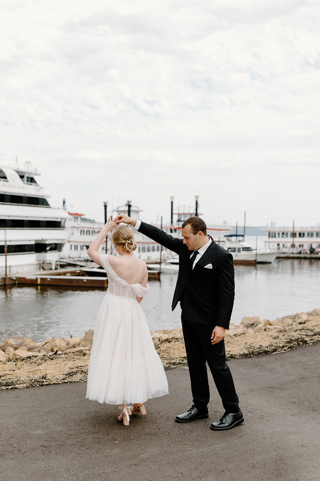 Groom twirls his bride in front of a yacht