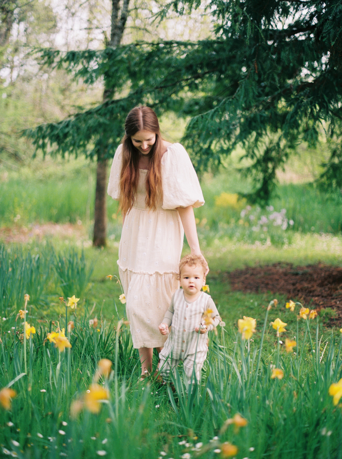 a young mom walks with her toddler through daffodils in Oregon