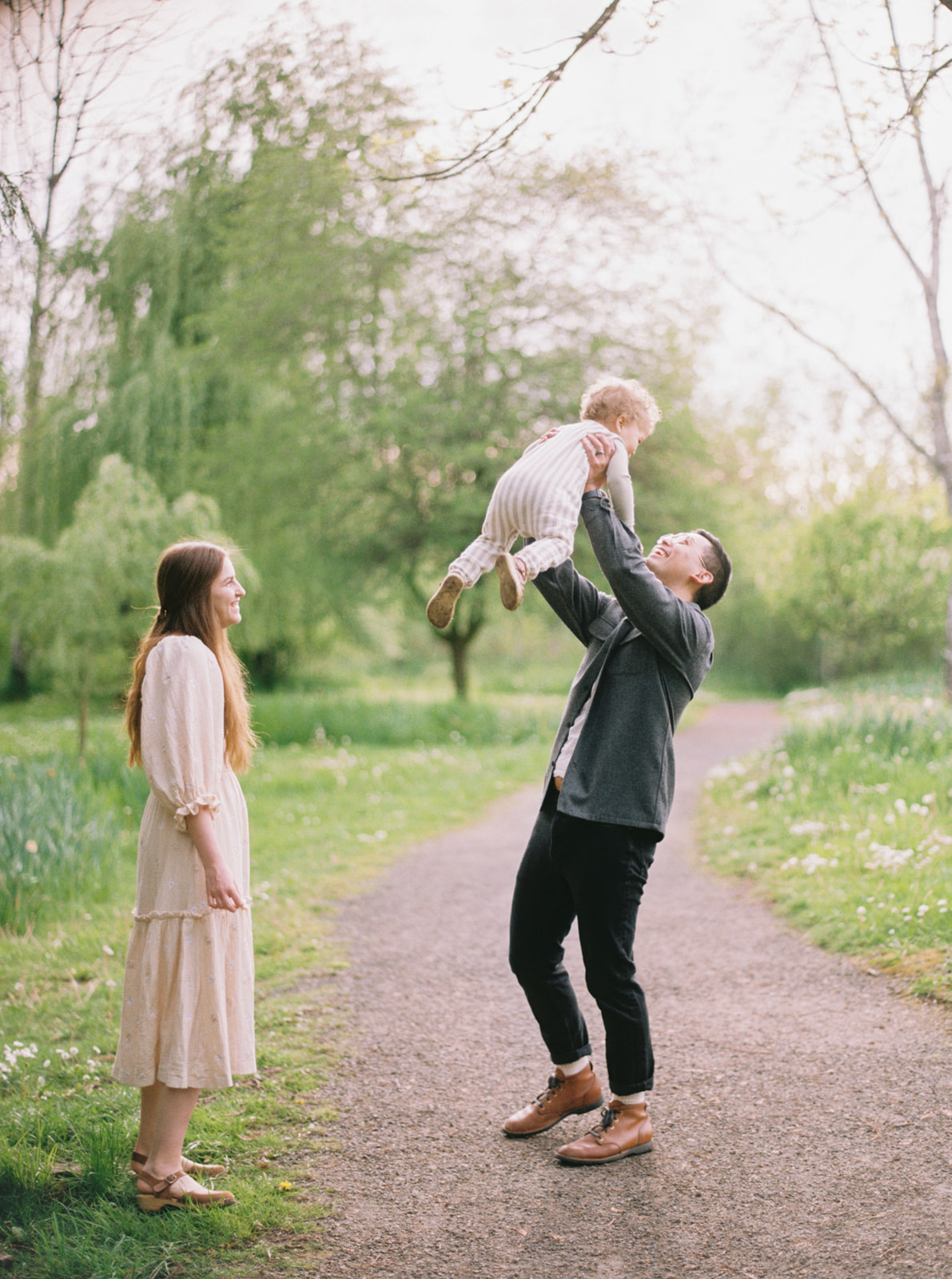 a dad playfully throws his toddler for their family photos in Portland Oregon