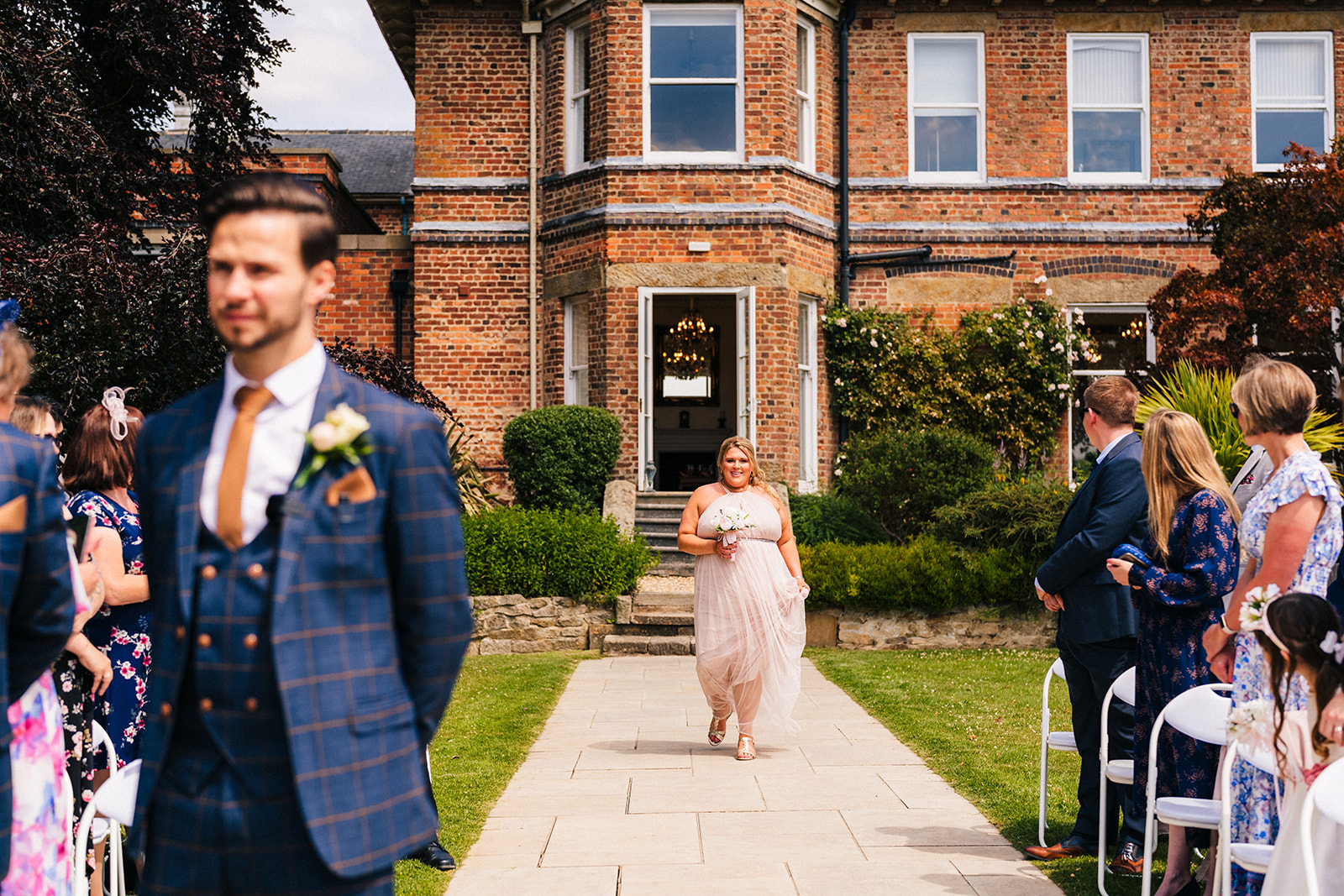 Shottle Hall Wedding Photography - a bridesmaid walking down the aisle during an outdoor wedding ceremony