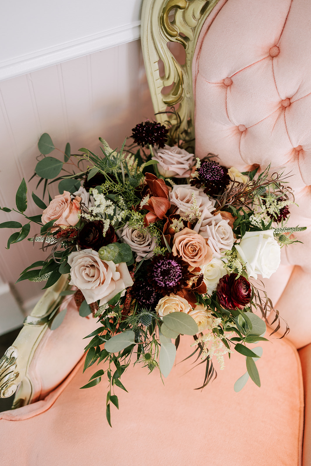 bouquet of wedding flowers in a vintage chair at over the vines event venue in edgerton wisconsin