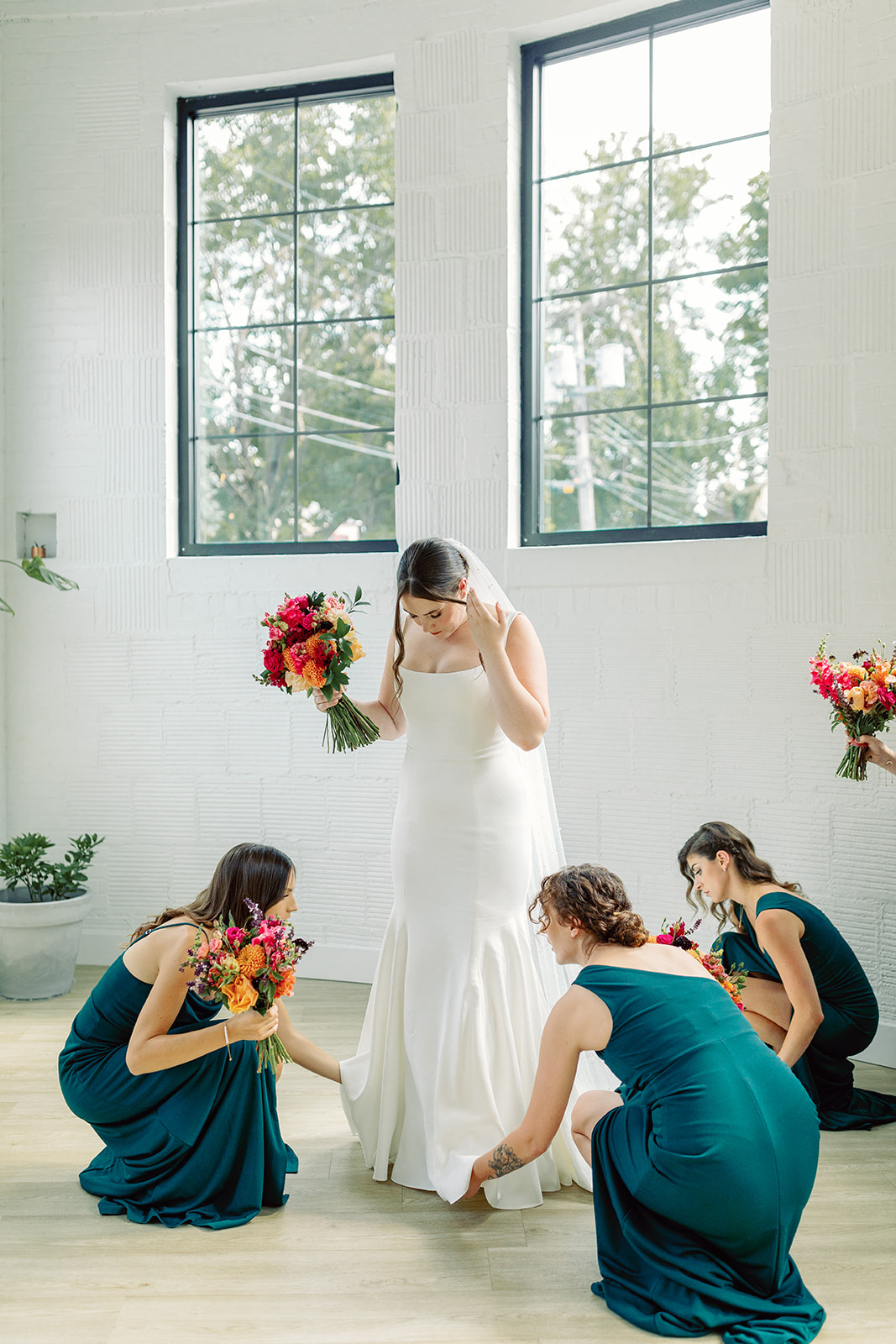 Bridesmaids helping the bride with her dress inside The Highline Rochester.