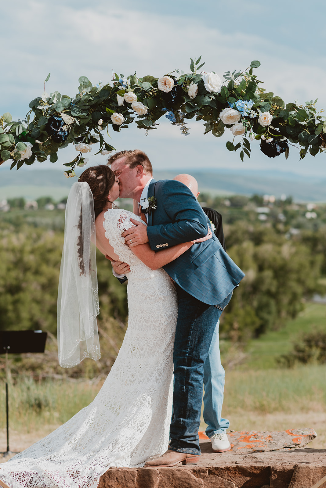 Couple kiss at the alter in front of mountains in their wedding attire at their wedding in Steamboat Springs, CO